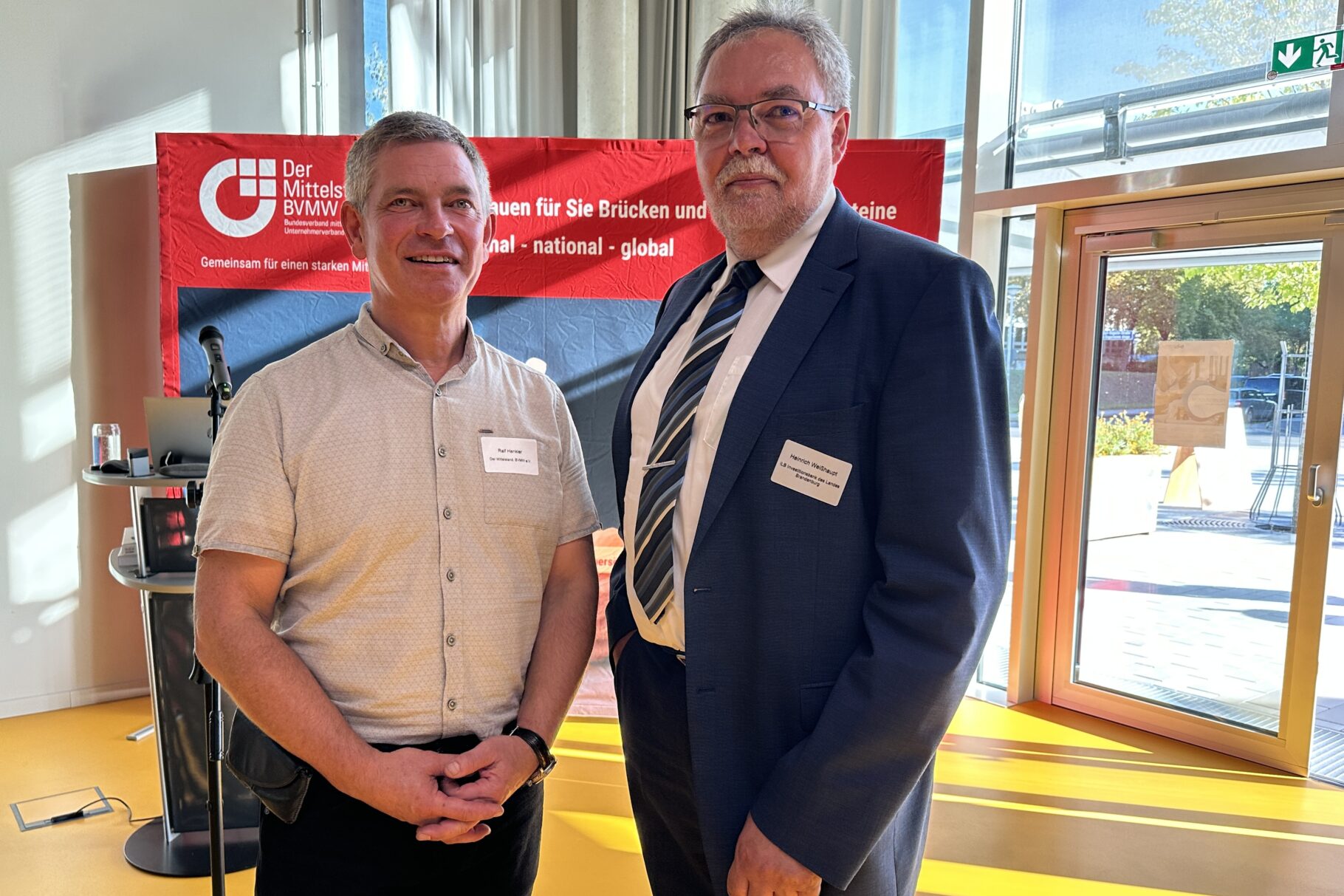 zwei Männer stehen vor einer Webetafel