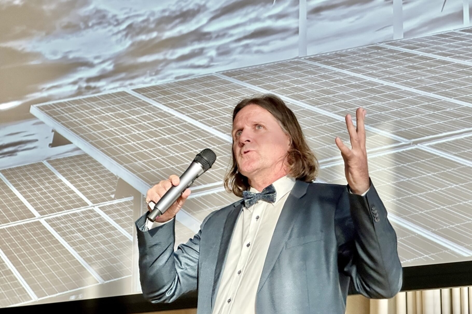 ein Mann hält ein Mikrofon in der Hand und hält einen Vortrag