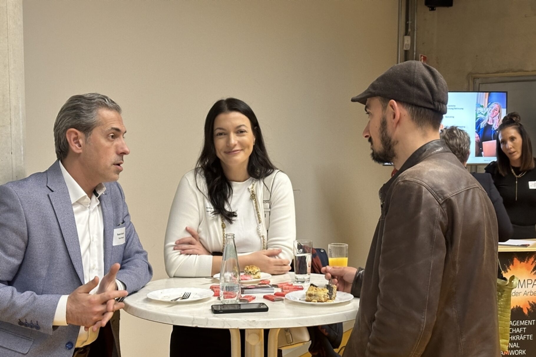 zwei Männer und eine Frau führen ein Gespräch um einen Stehtisch