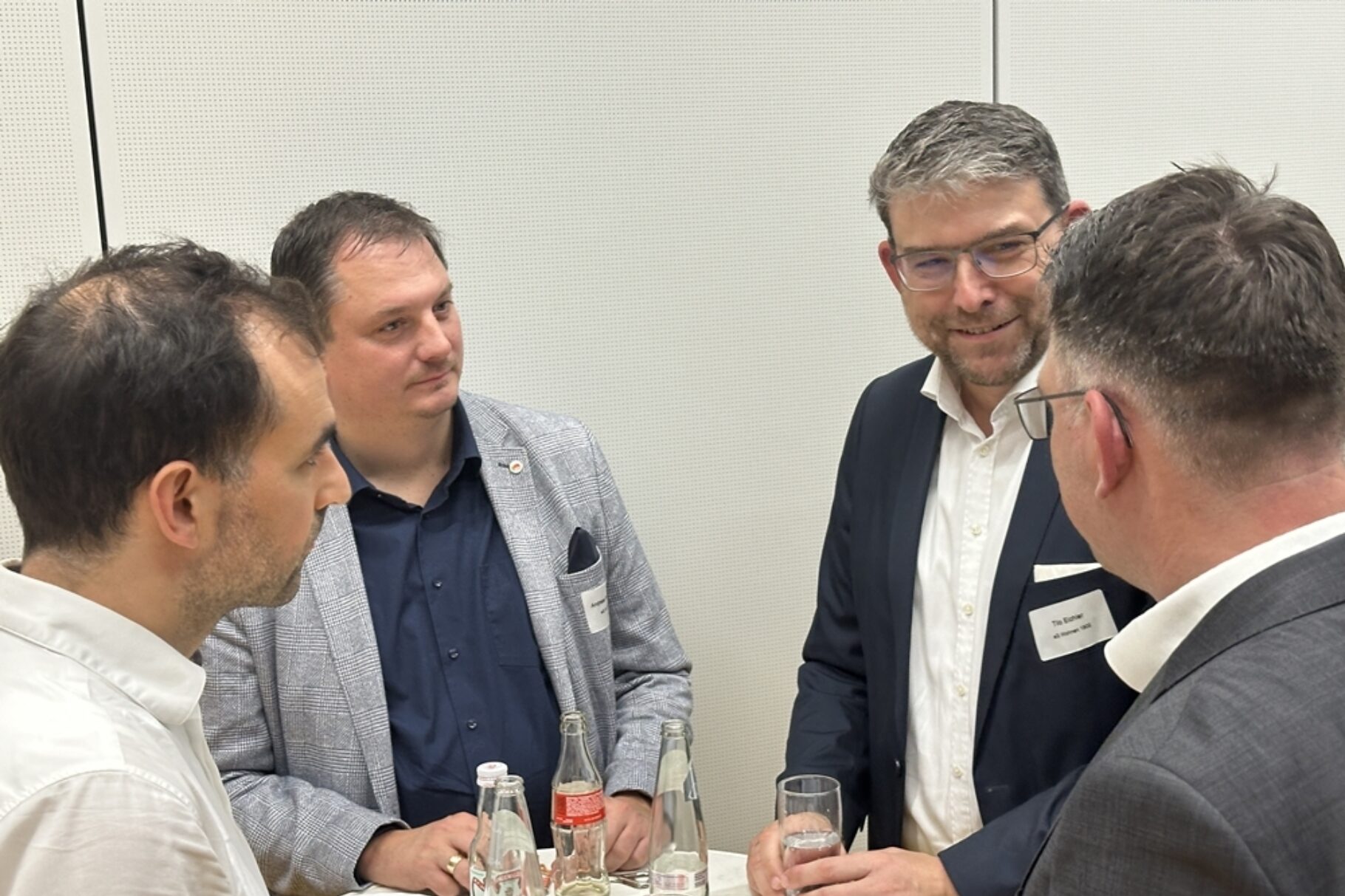 4 Männer unterhalten sich an einem Stehtisch