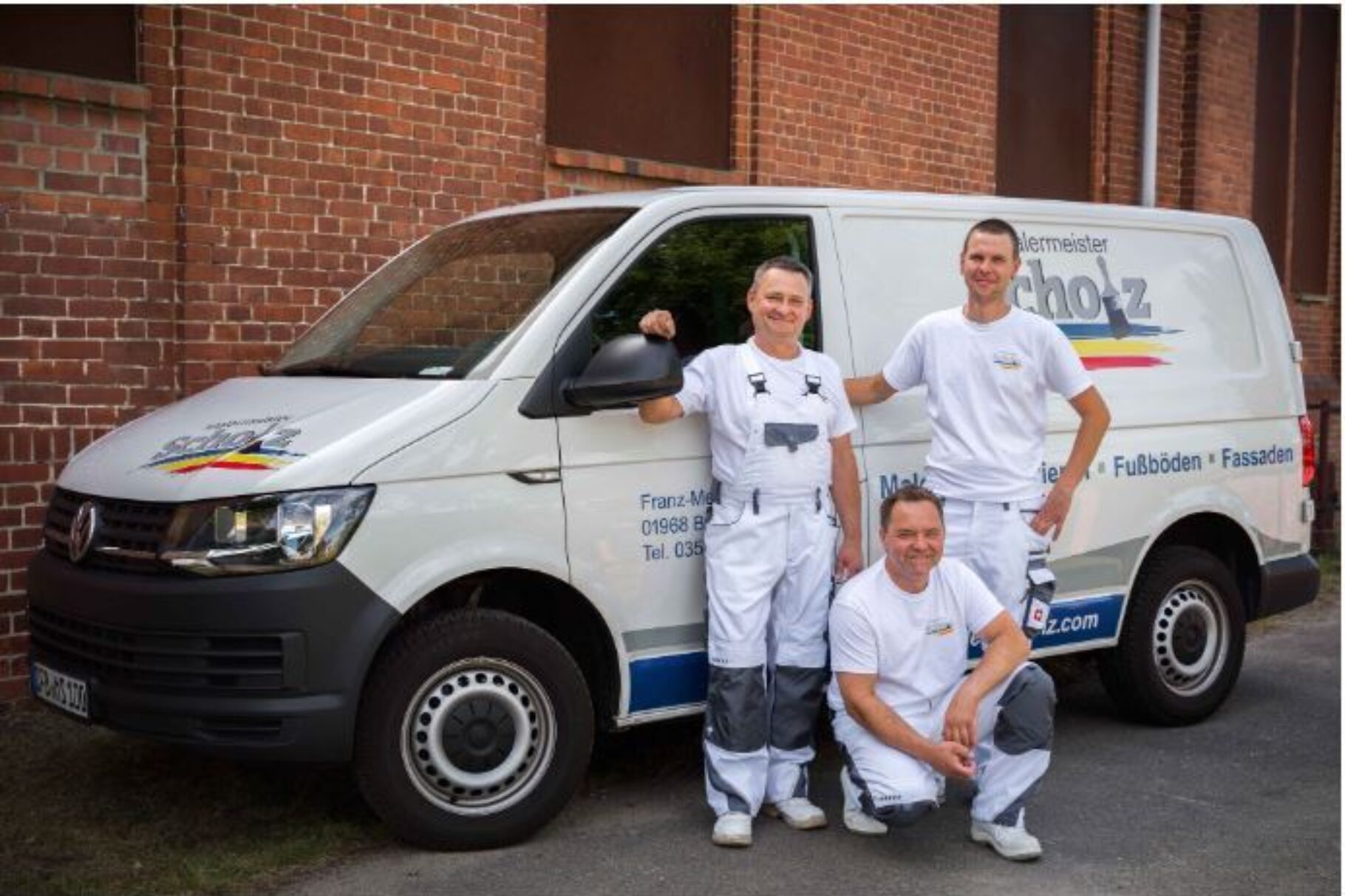Drei Männer stehen vor einem Firmentransporter