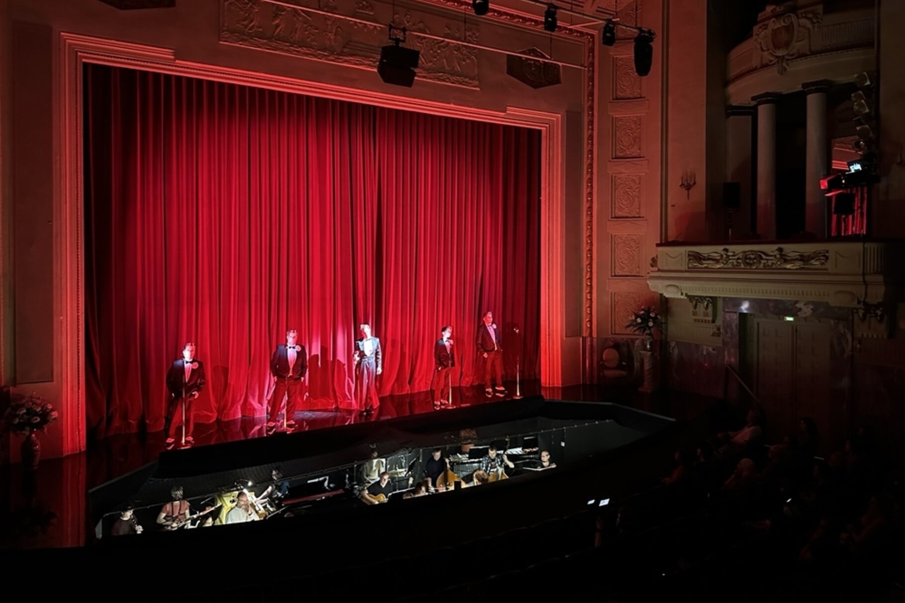 5 Schauspieler*innen stehen vor einem Vorhang auf der Bühne