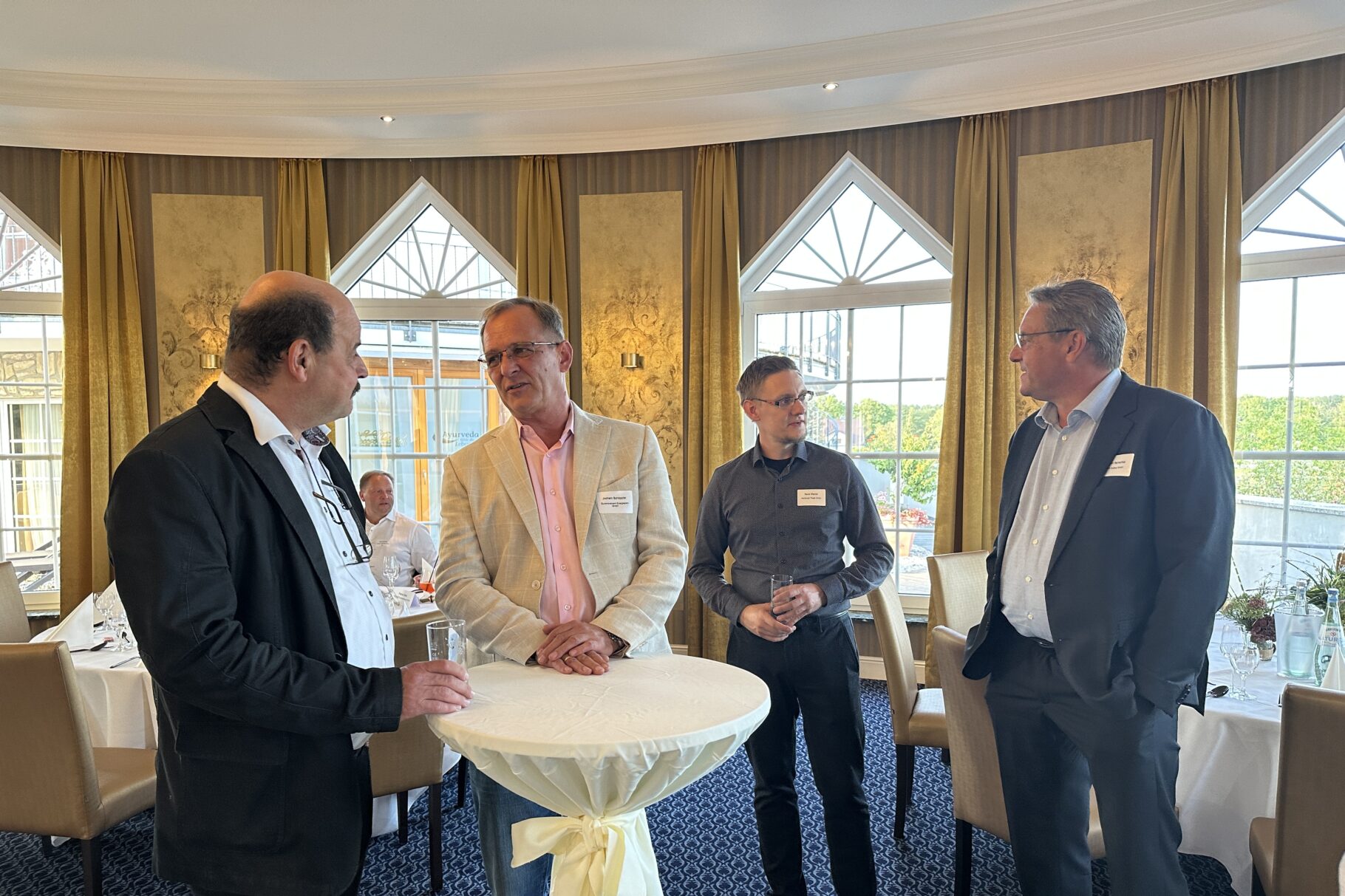 Männer stehen um einen Tisch und unterhalten sich