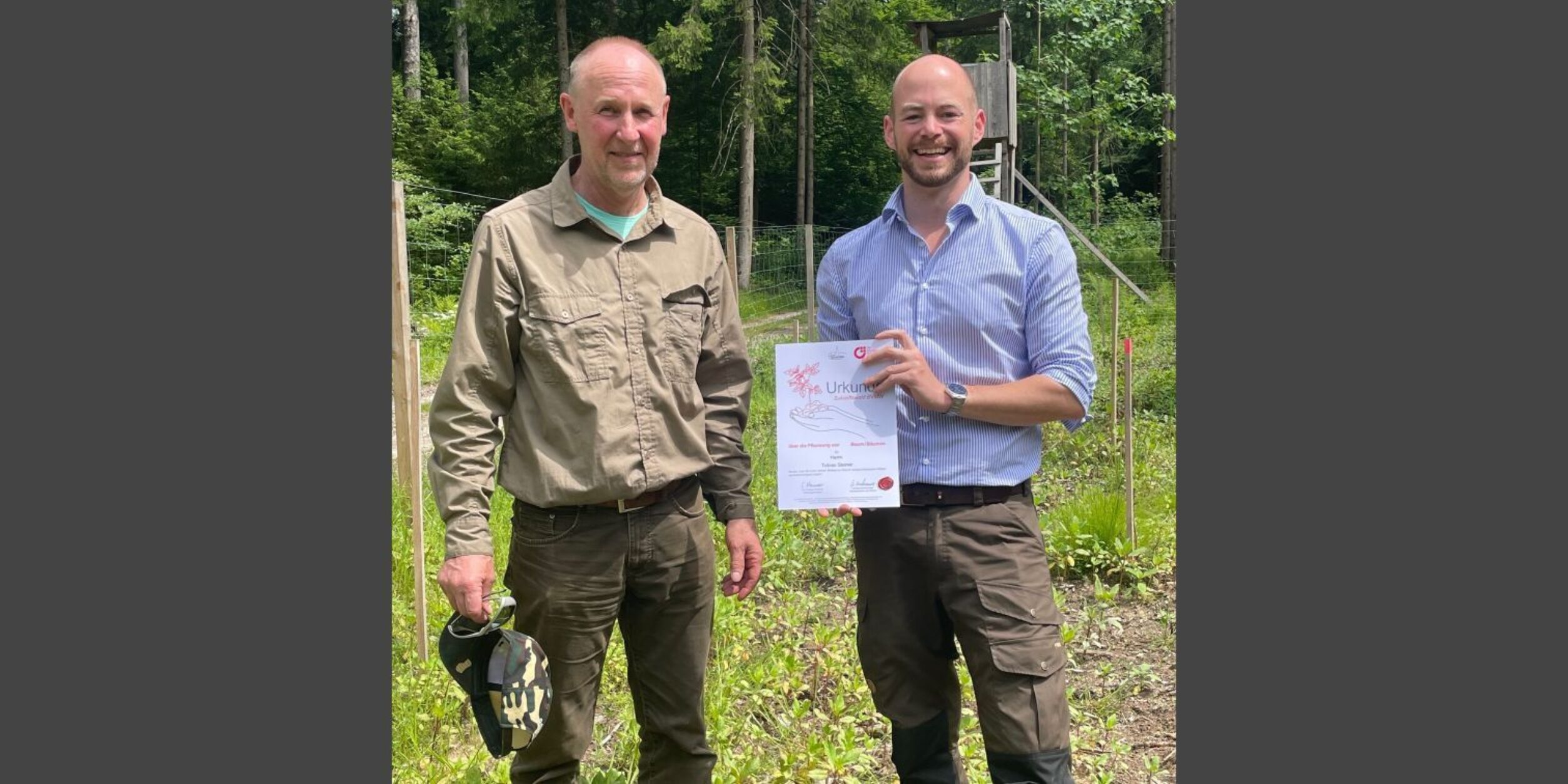 Foto: Herr Fischer übergibt Herrn Steiner einen Paten-Baum im BVMW Zukunftswald; Copyright: Kirchermeier