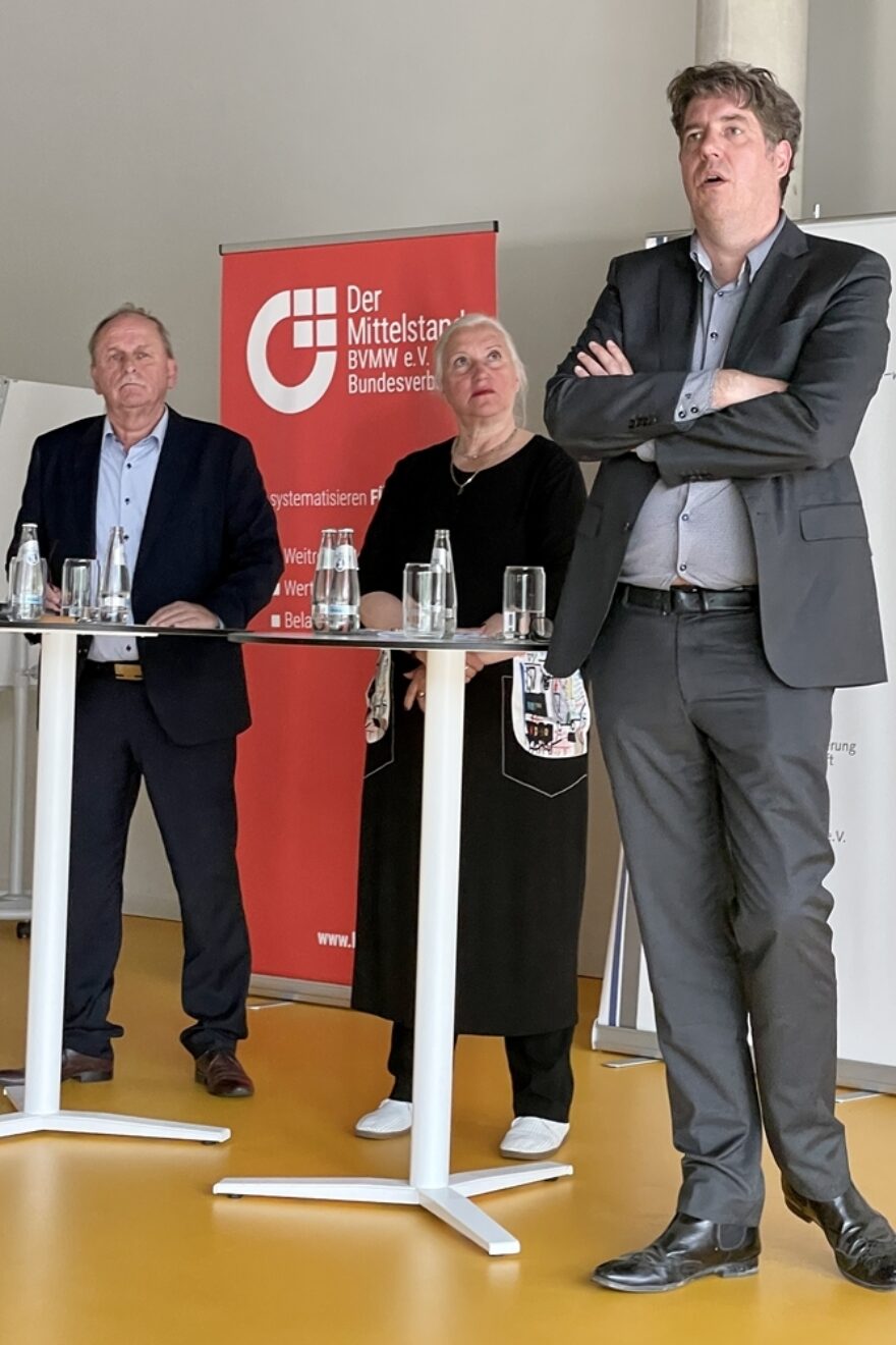 3 Menschen unterhalten sich an Stehtischen
