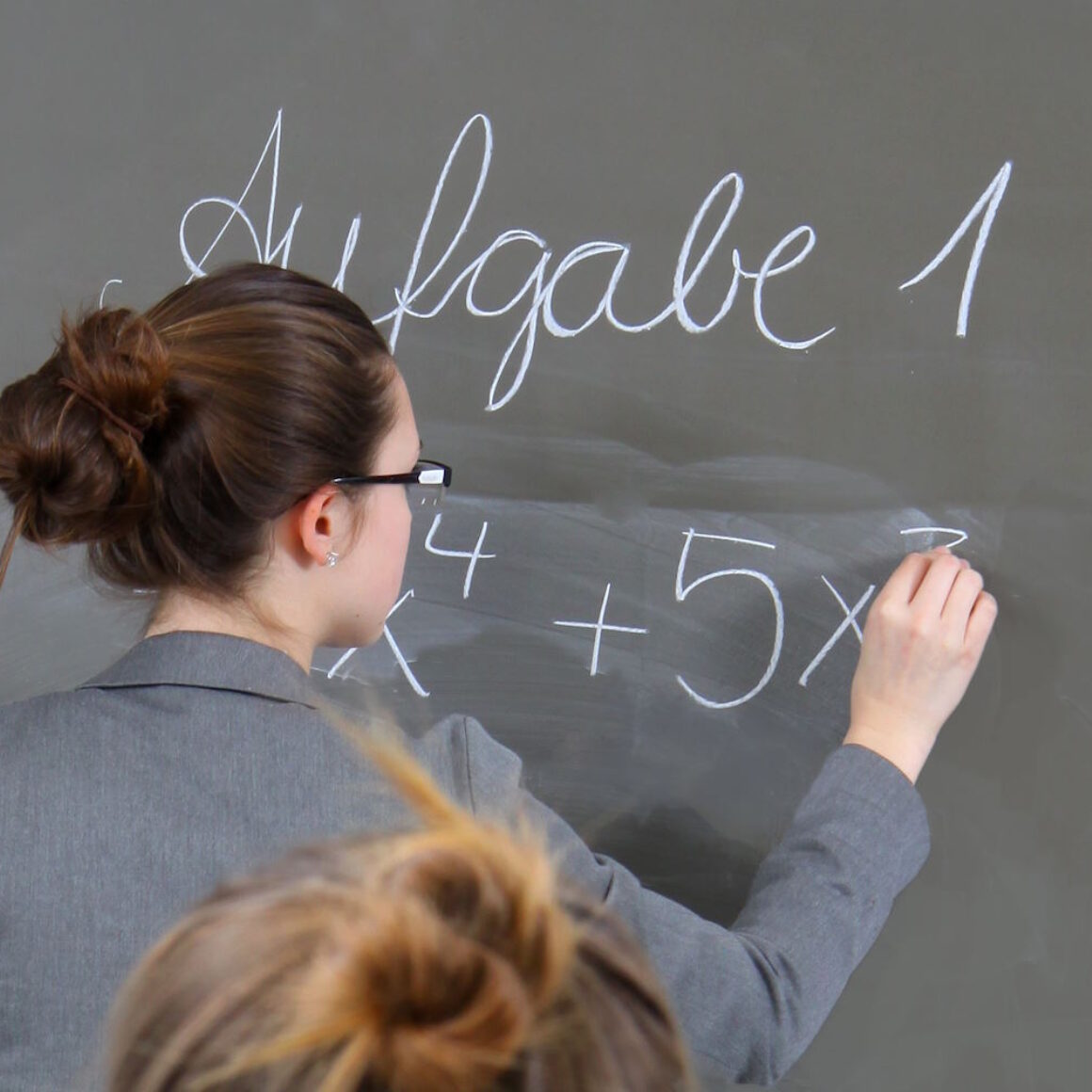 Eine Frau schreibt etwas an eine Schultafel