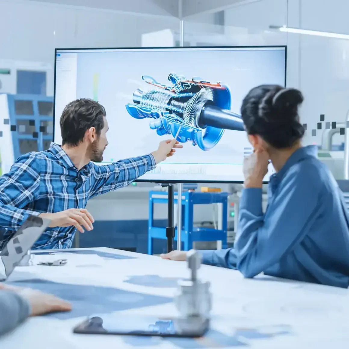 Mehrere Personen sitzen in einer Besprechung zusammen und schauen auf einen Bildschirm