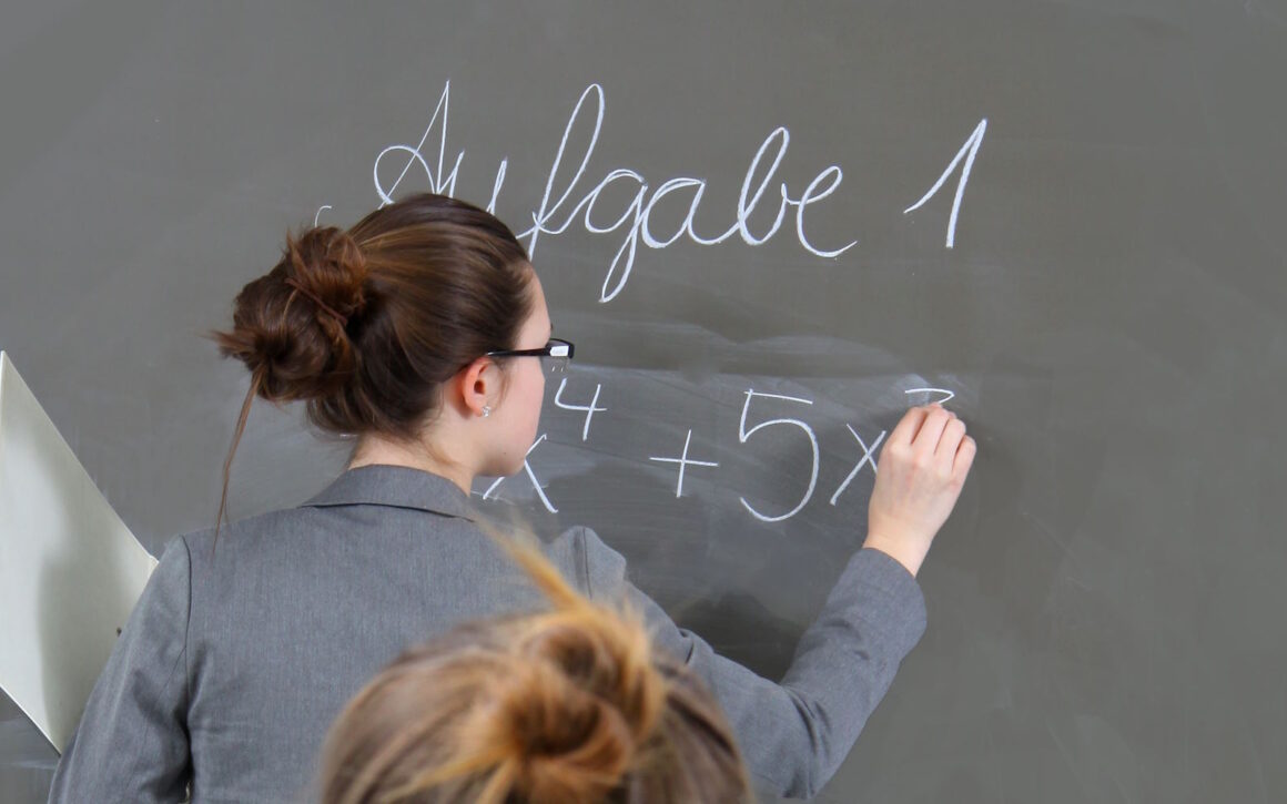 Eine Frau schreibt etwas an eine Schultafel