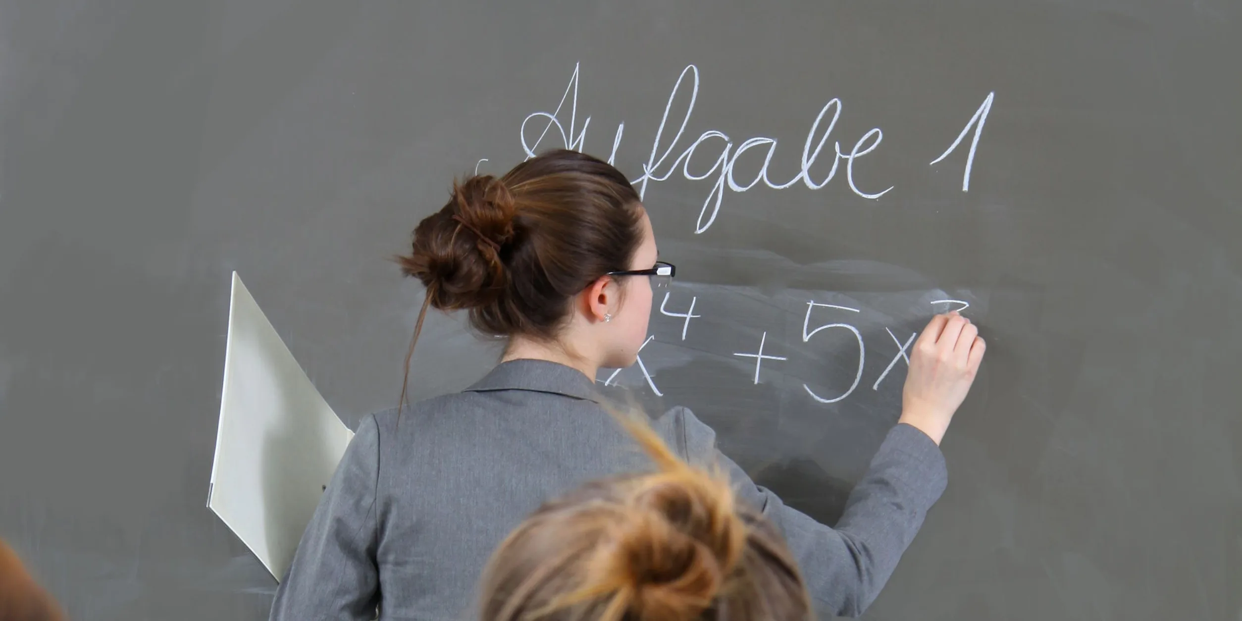 Eine Frau schreibt etwas an eine Schultafel