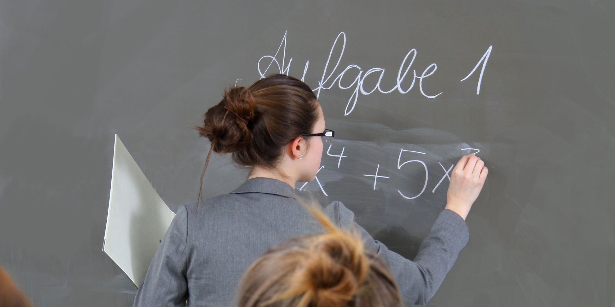 Eine Frau schreibt etwas an eine Schultafel