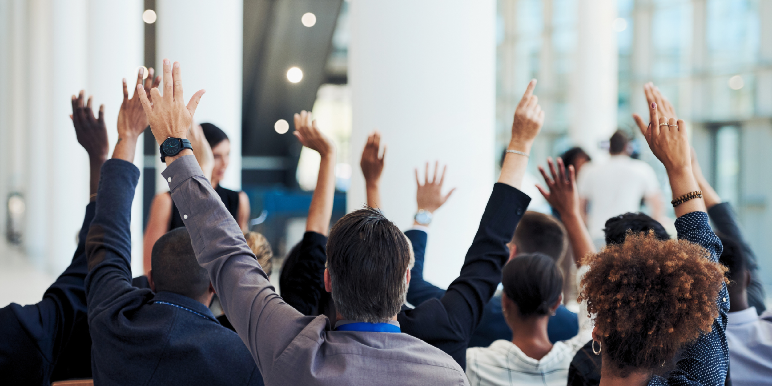 Menschen mit gehobenen Armen die abstimmen.