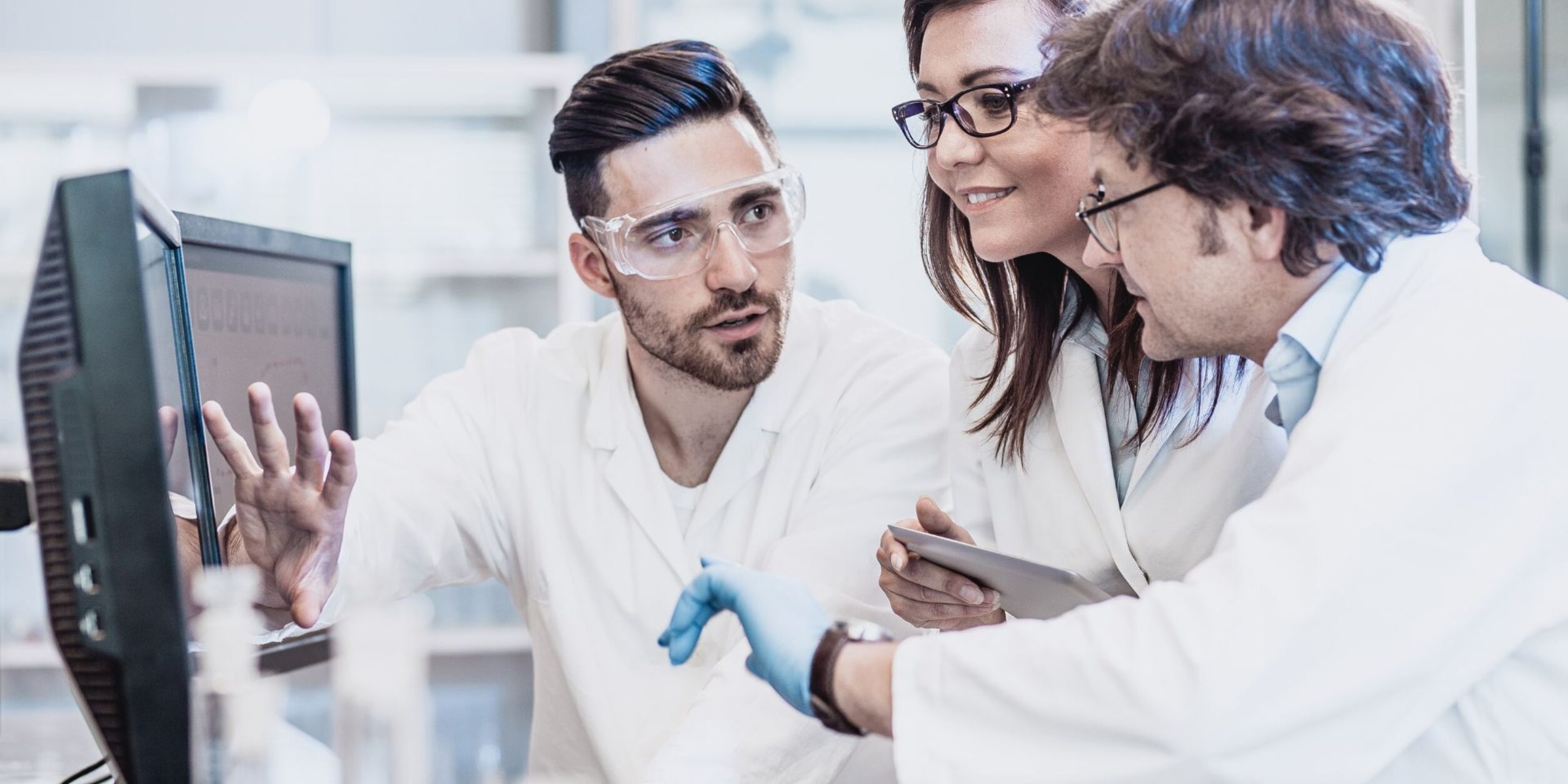 3 Wissenschaftler besprechen sich am PC-Bildschirm