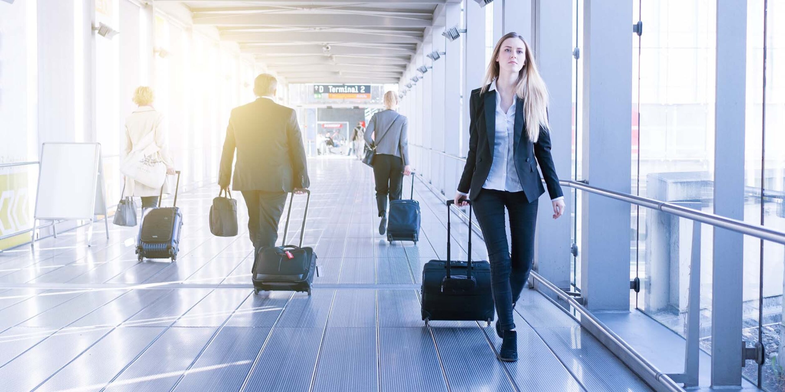 Reisende mit Rollkoffern im Flughafen