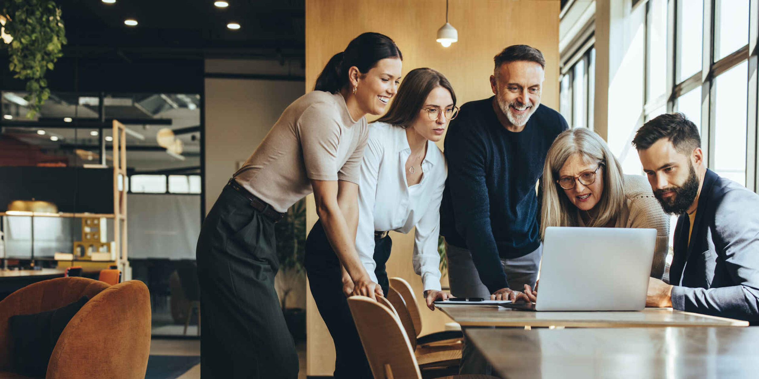 Eine Gruppe von Menschen schaut gemeinsam auf einen Laptop