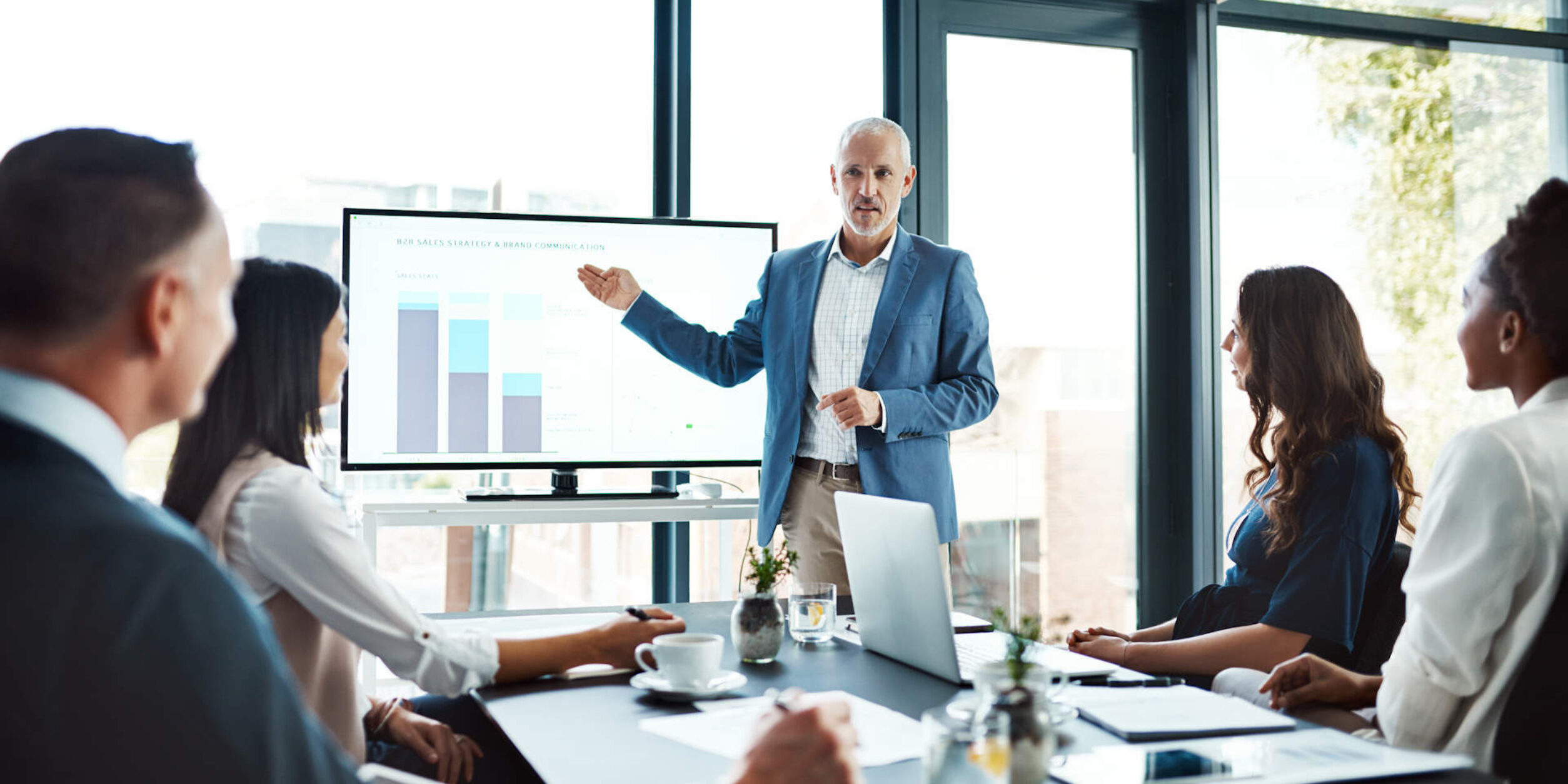 Ein Mann präsentiert Diagramme auf einem großen Bildschirm