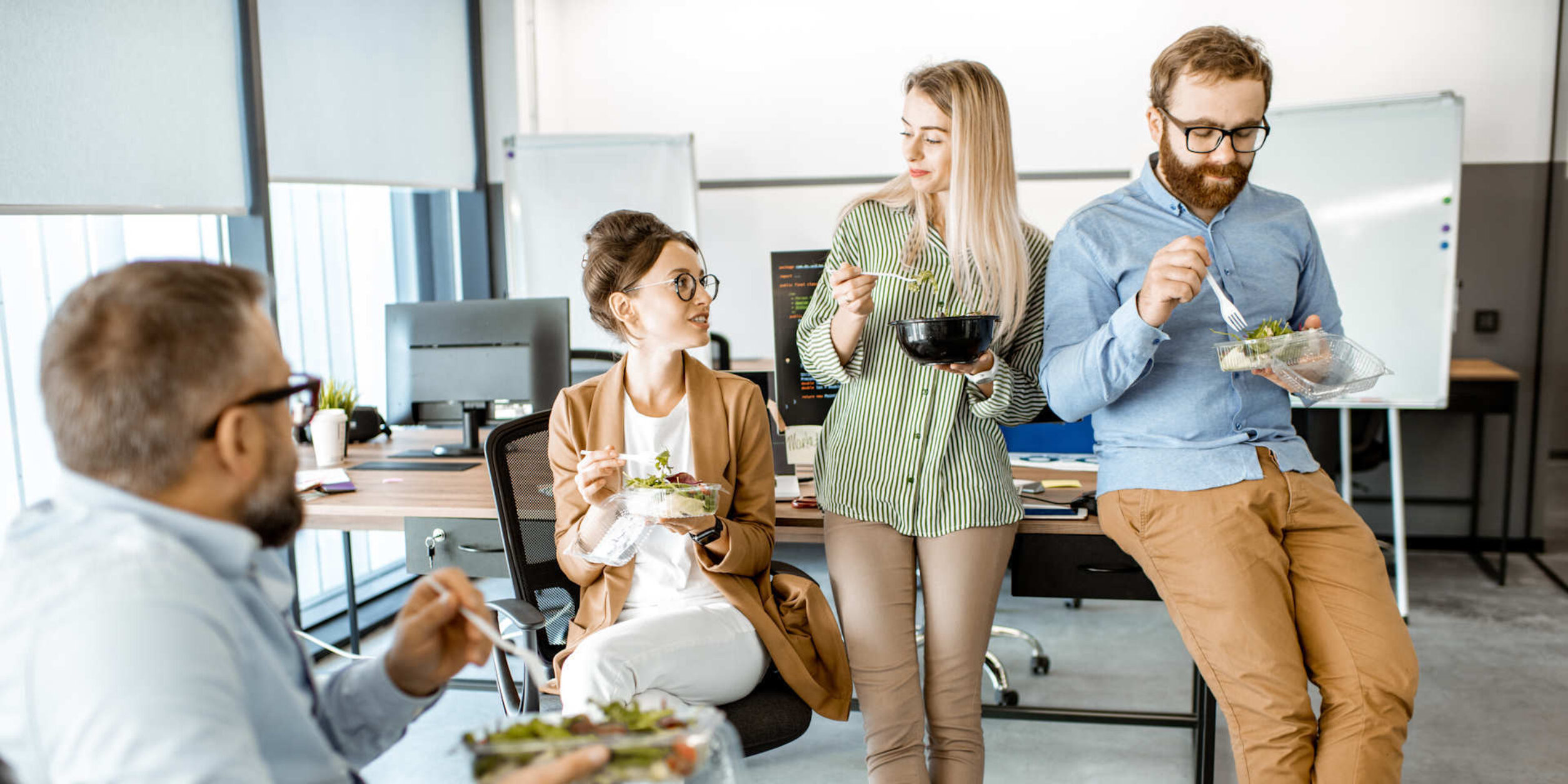 Eine Gruppe von Menschen essen zusammen im Büro