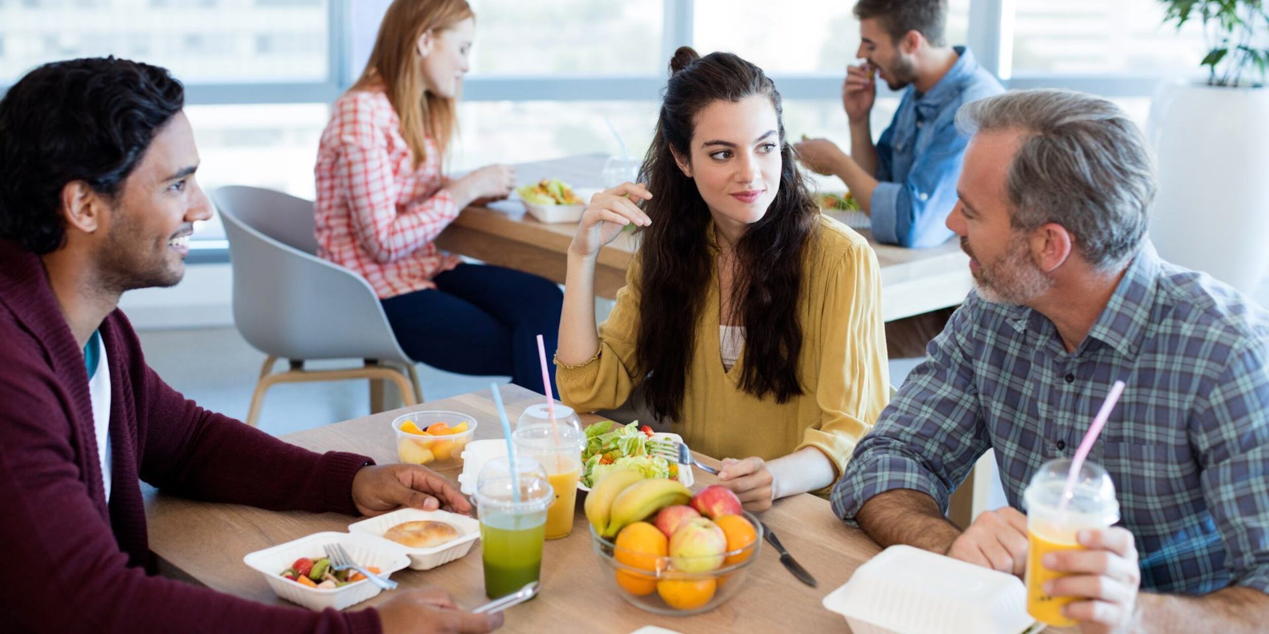 3 Personen sitzen an einem mit gesunden Lebensmitteln gedeckten Frühstückstisch
