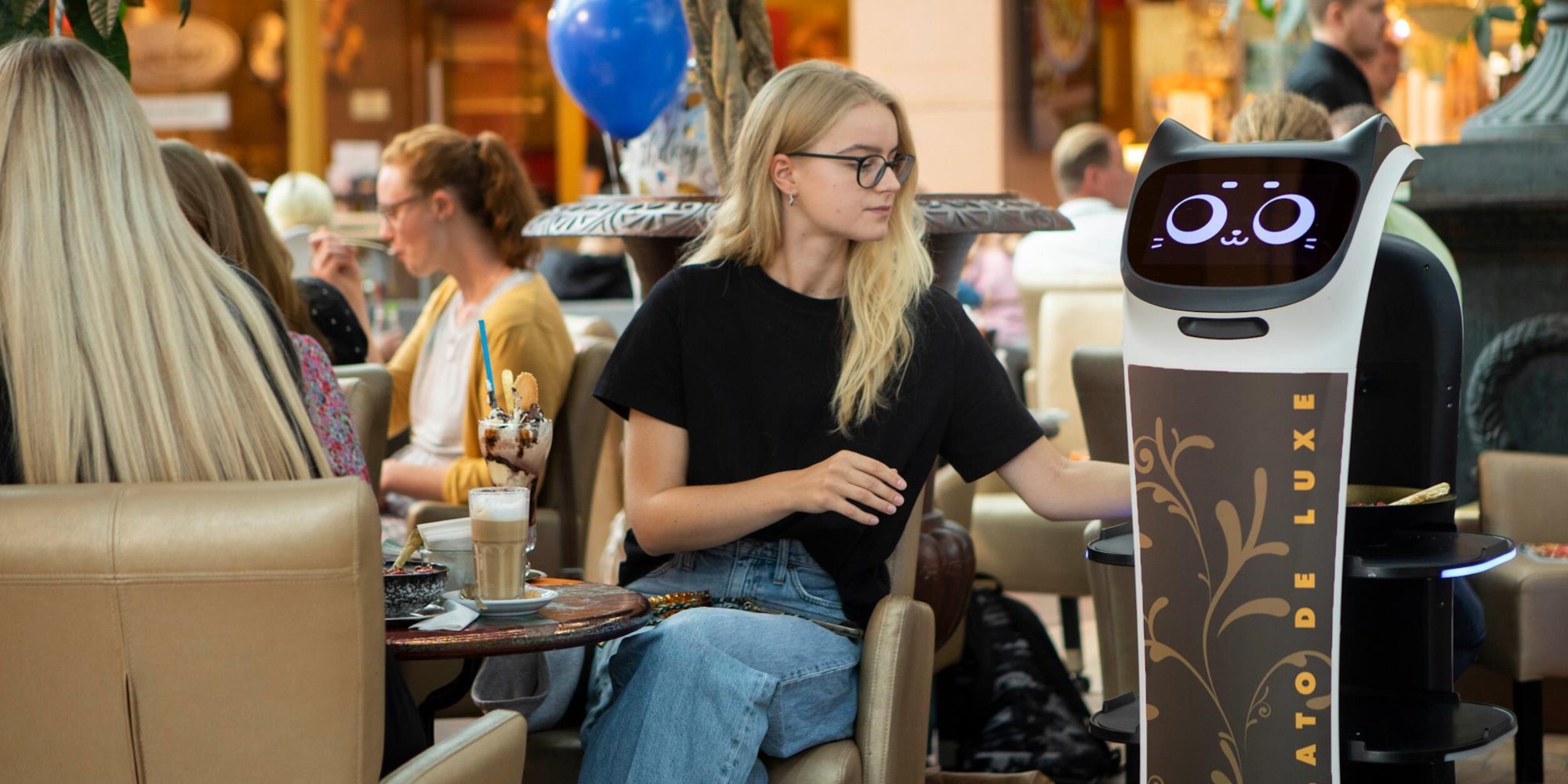 Ein Gast in einer Eisdiele wird von einem Roboter bedient
