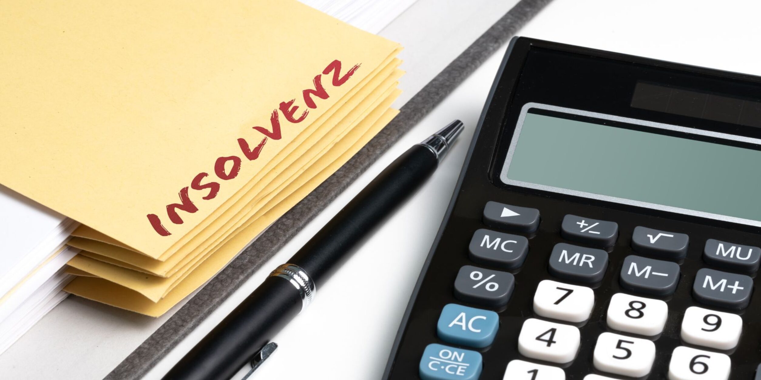 Ein Insolvenzordner und ein Taschenrechner nebenan