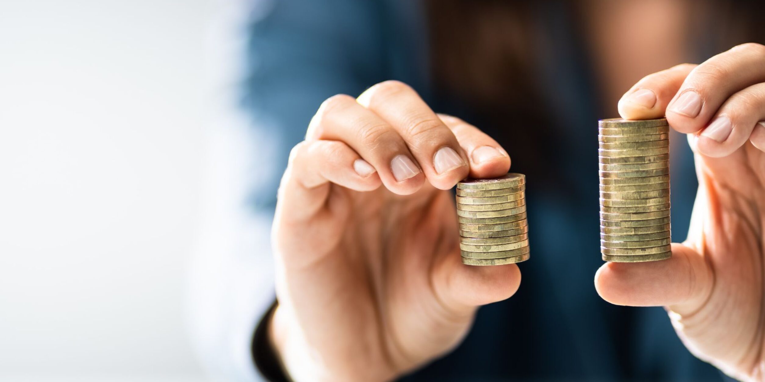 Eine Person hält 2 Stabel Münzgeld in der Hand