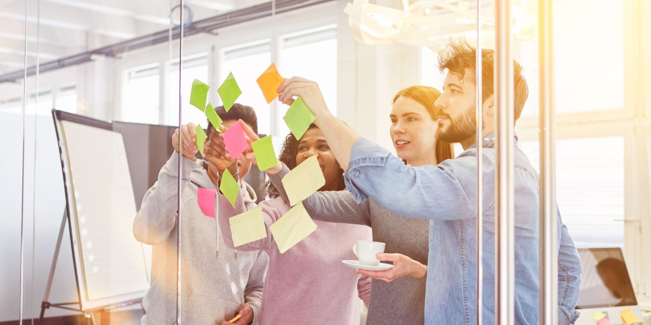 Mehrere Personen kleben Klebenotizen an eine Scheibe und betrachten die Ergebnisse