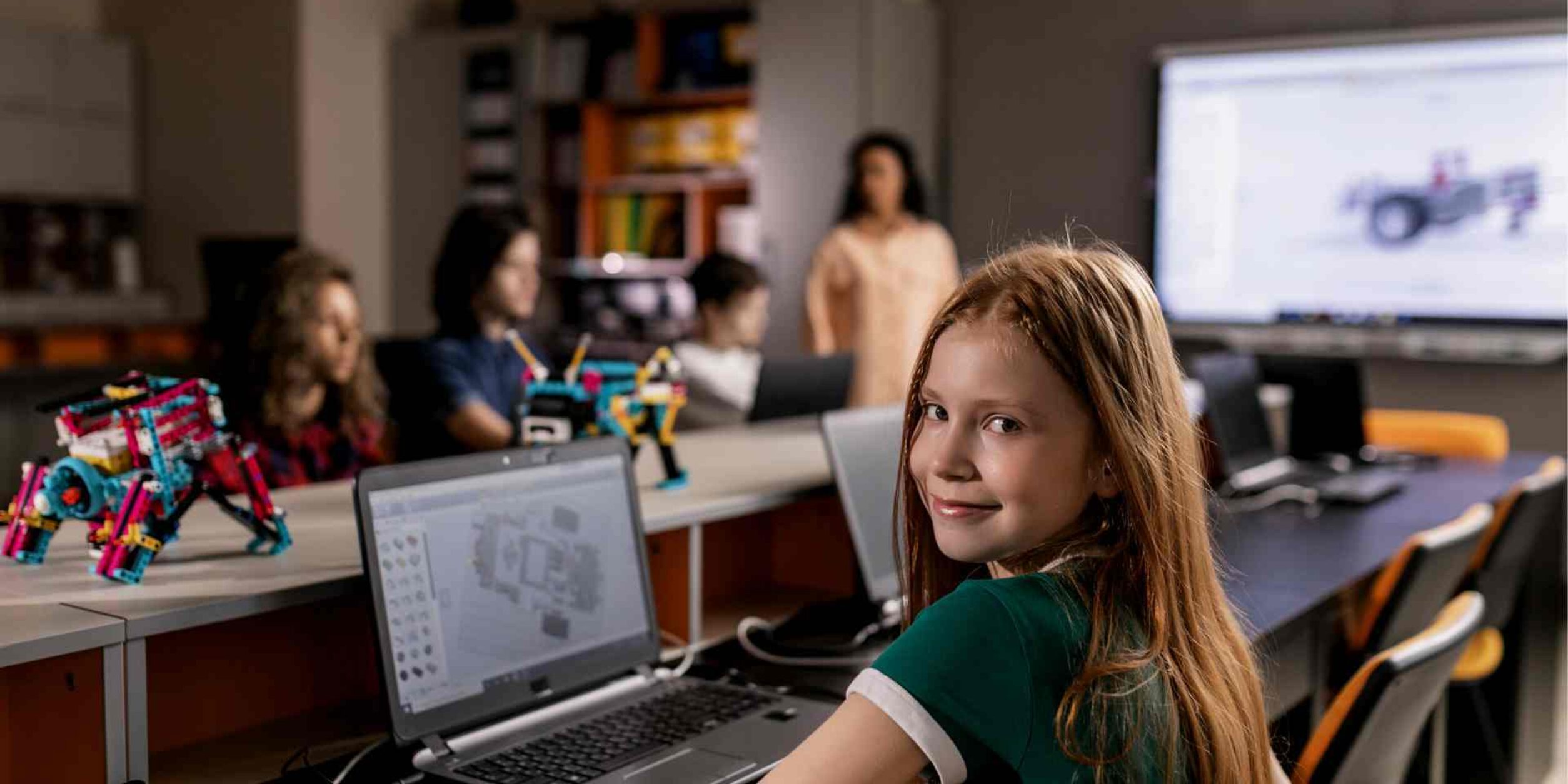 In einem Klassenraum vor einem Laptop sitzende Schülerin