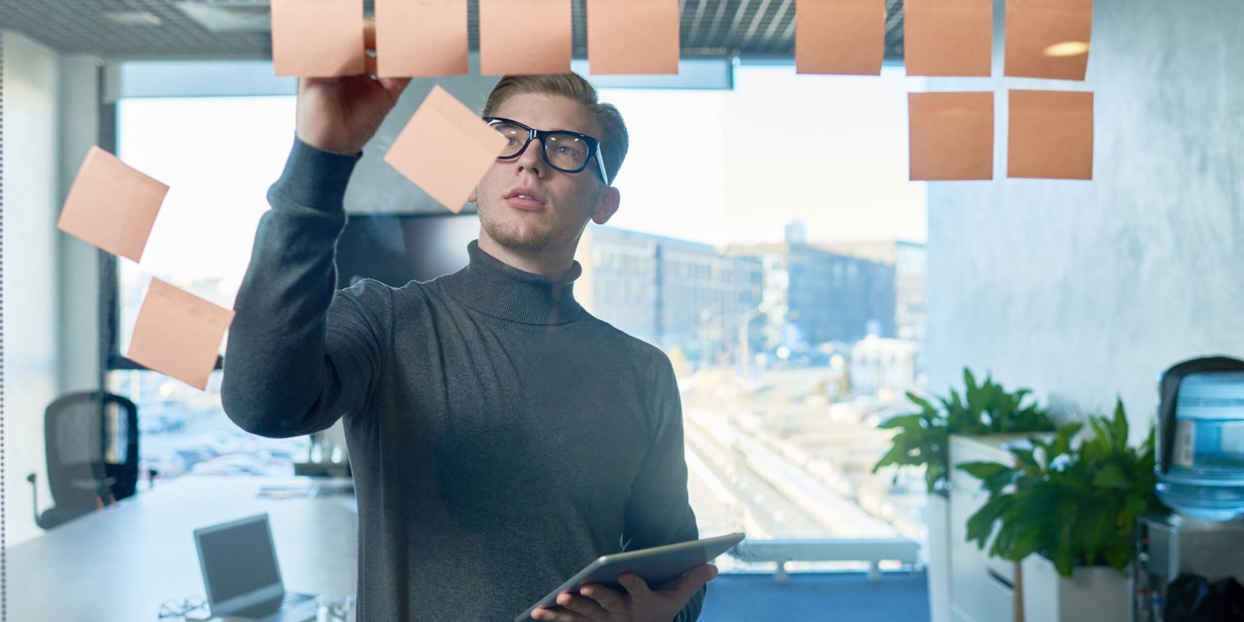 Ein Mann klebt Zettelnotizen an eine Glaswand