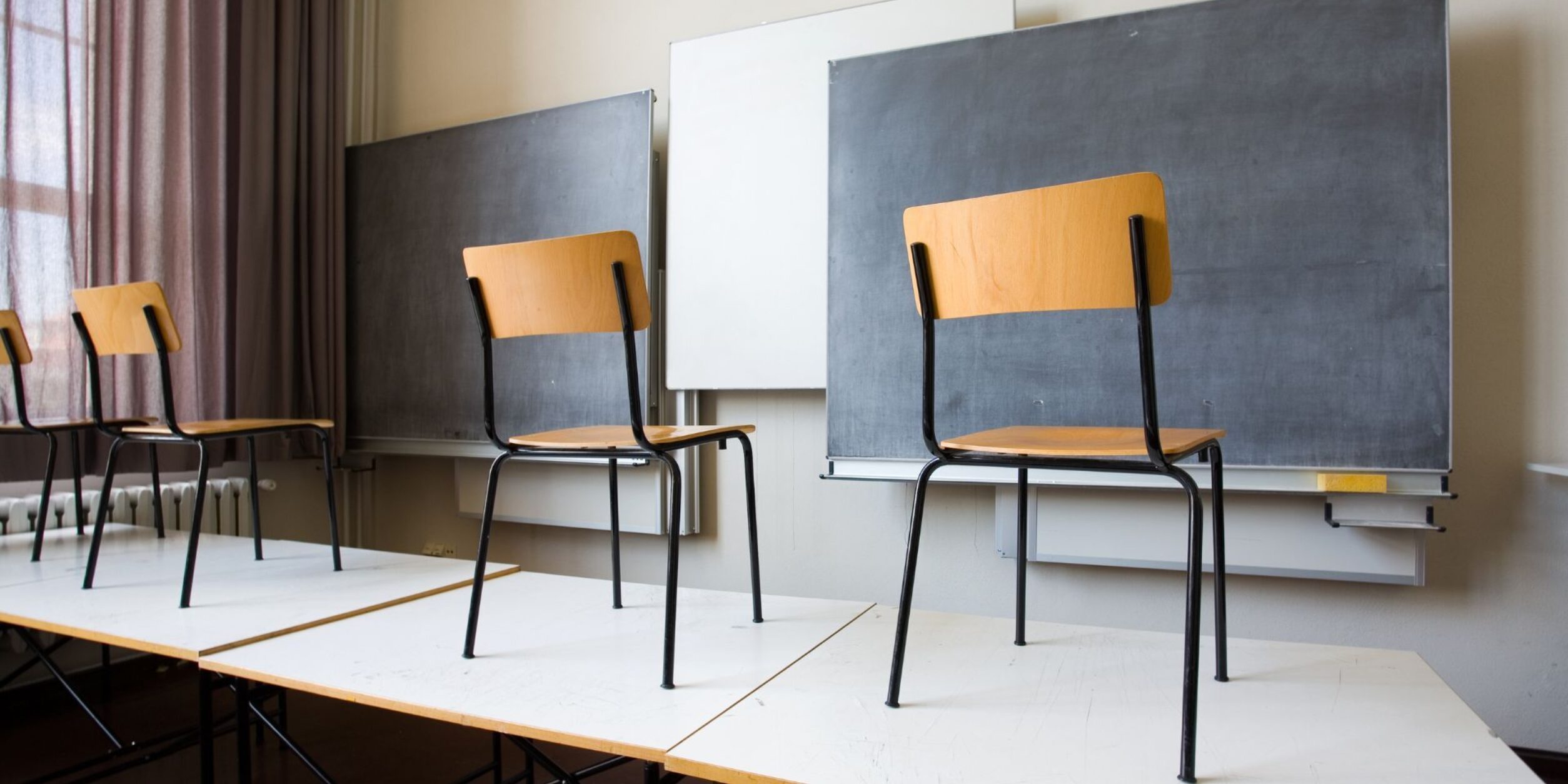 Stühle stehen in einem Klassenzimmer auf den Tischen