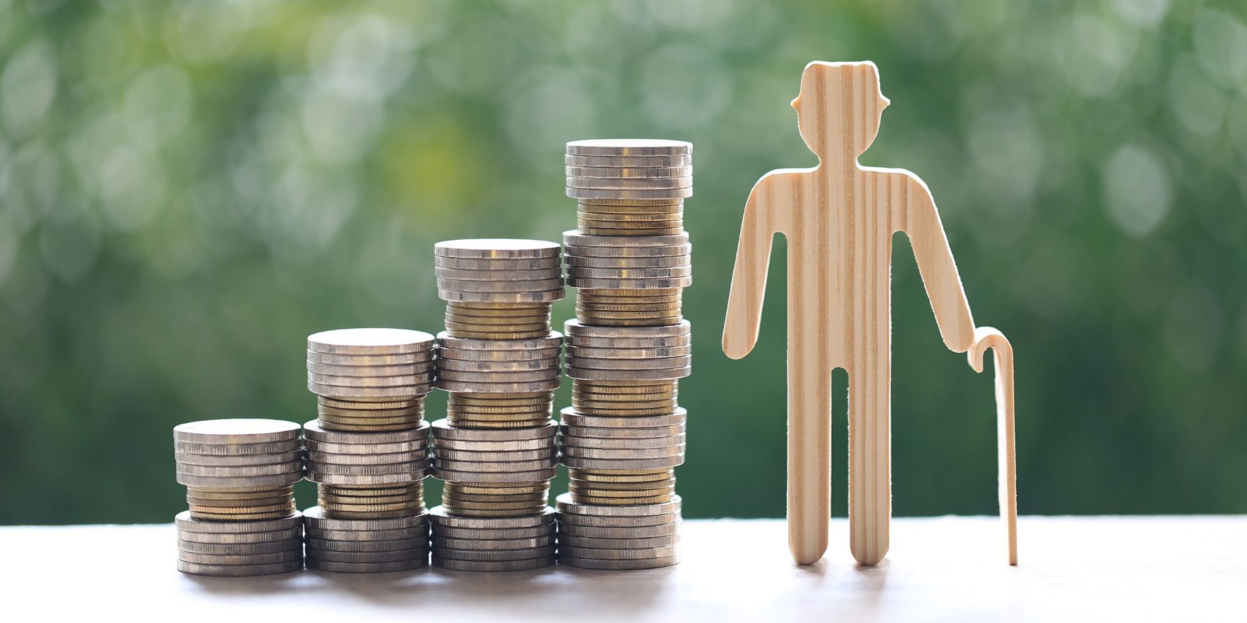 Aufsteigend gestapelte Münzen neben einem alten Holzmännchen