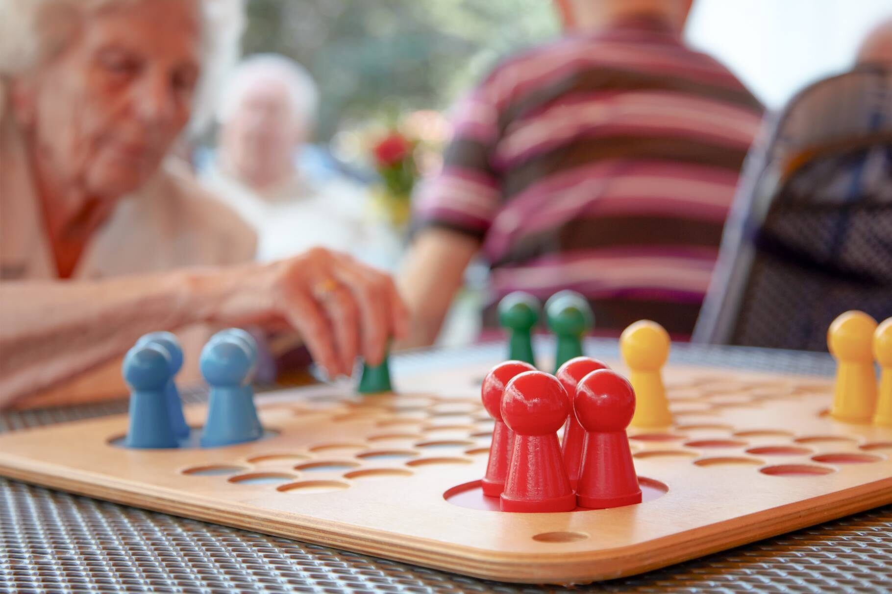 Eine ältere Frau spielt „Mensch ärgere dich nicht“