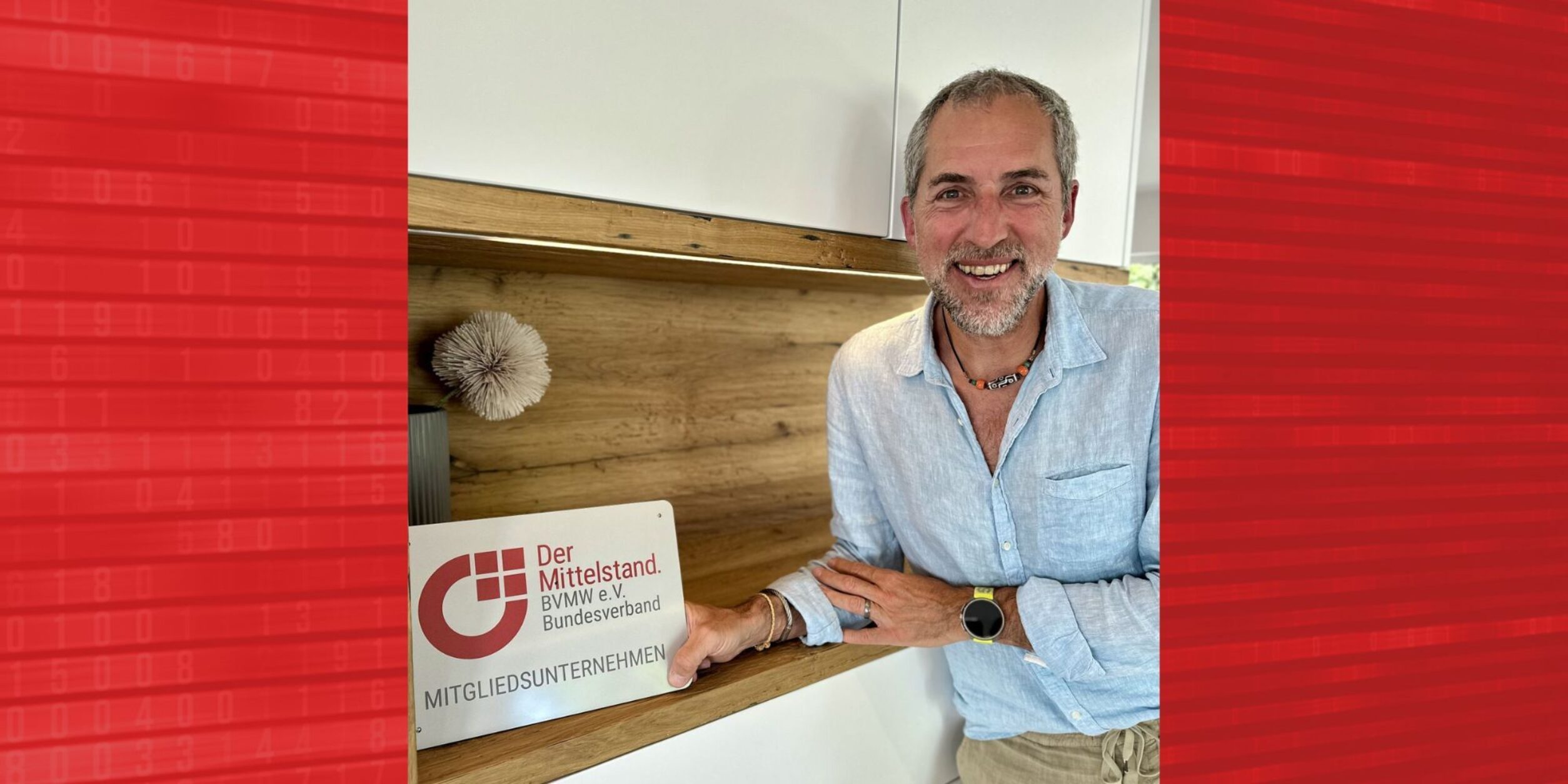 Boris Bregar mit BVMW Mitgliedsunternehmen Schild, Halbportrait, Schild in der rechten Hand