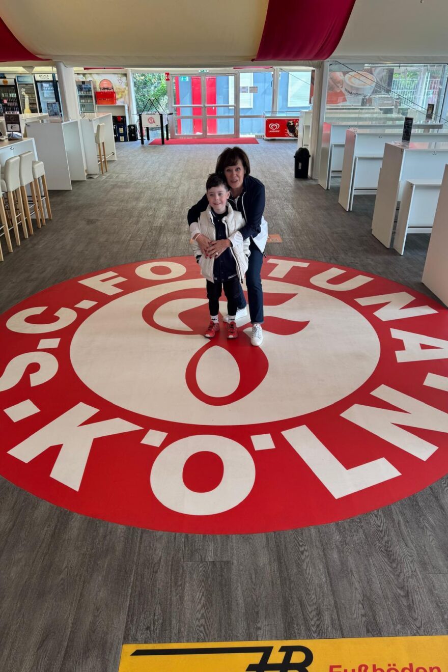 Logo Fortuna Köln am Boden mit Dagmar Maier und einem Kind