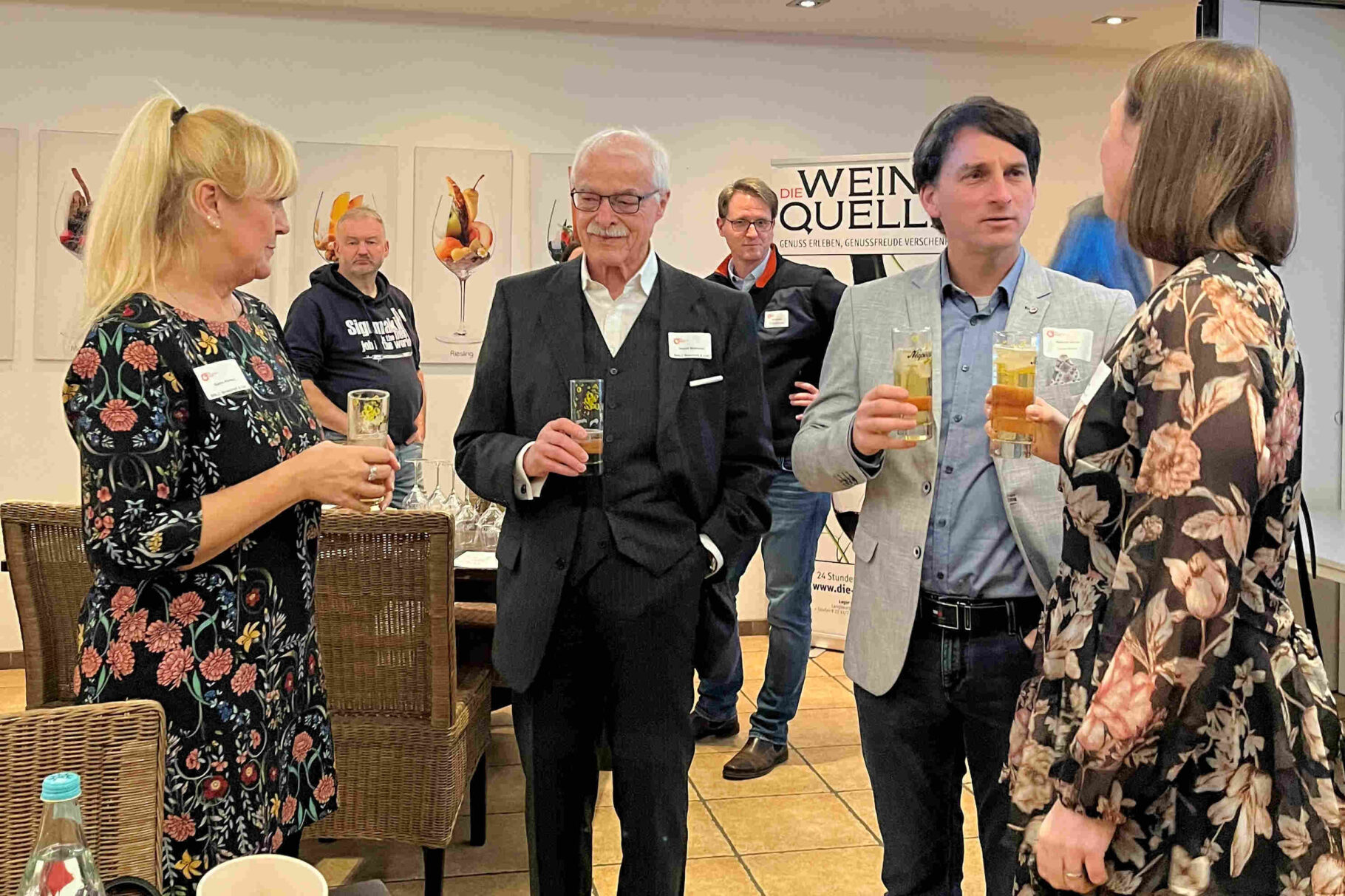 Teilnehmer stehen mit Gläsern und diskutieren