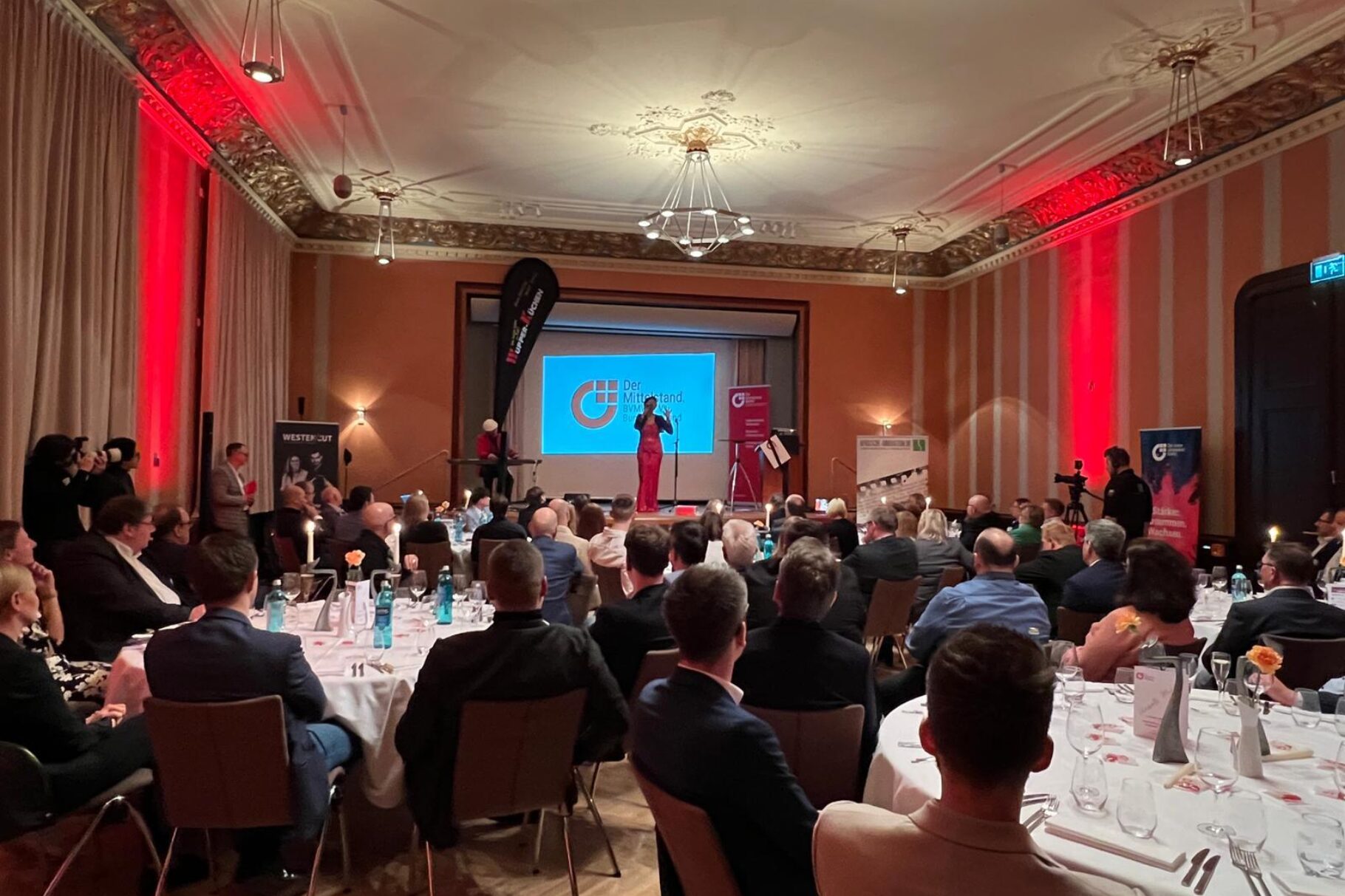 Gäste an gedeckten Tischen vor der Bühne