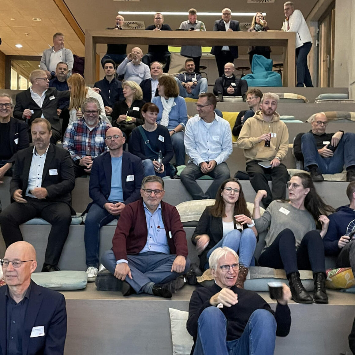 Teilnehmer sitzen auf einer Sitztreppe  in Erwartung der Veranstalung