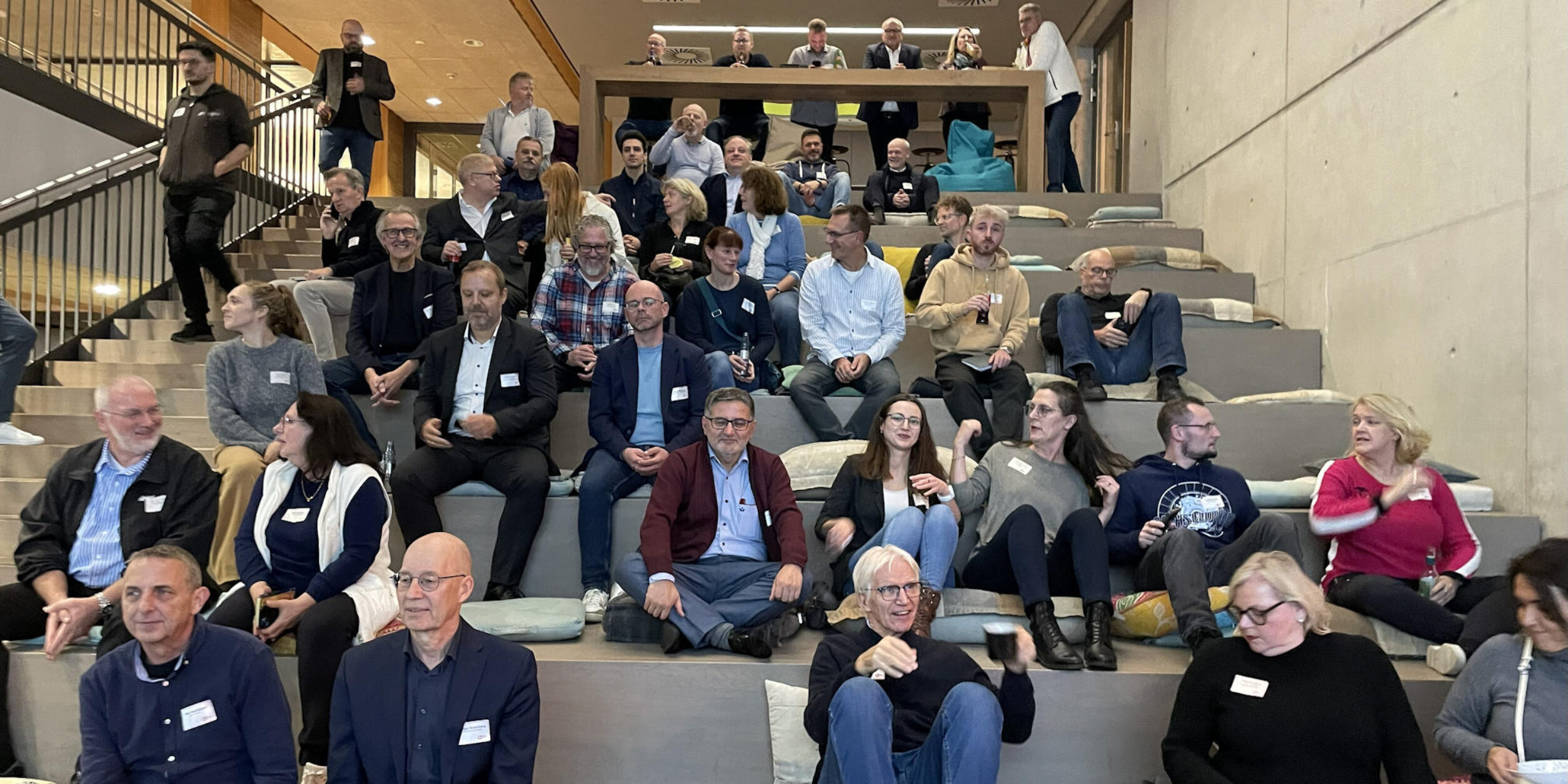 Teilnehmer sitzen auf einer Sitztreppe  in Erwartung der Veranstalung