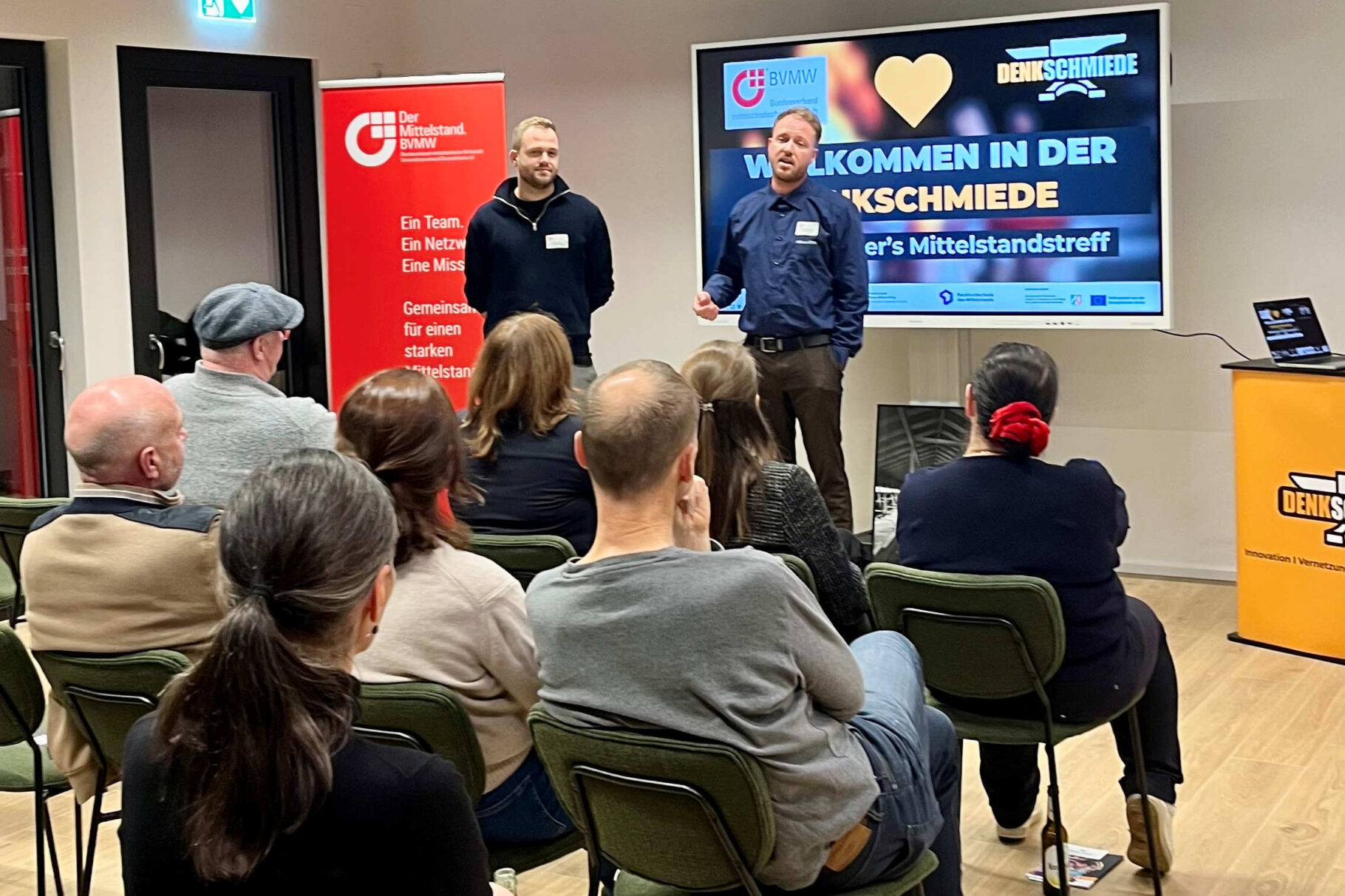 Referenten vor Monitor und Teilnehmern