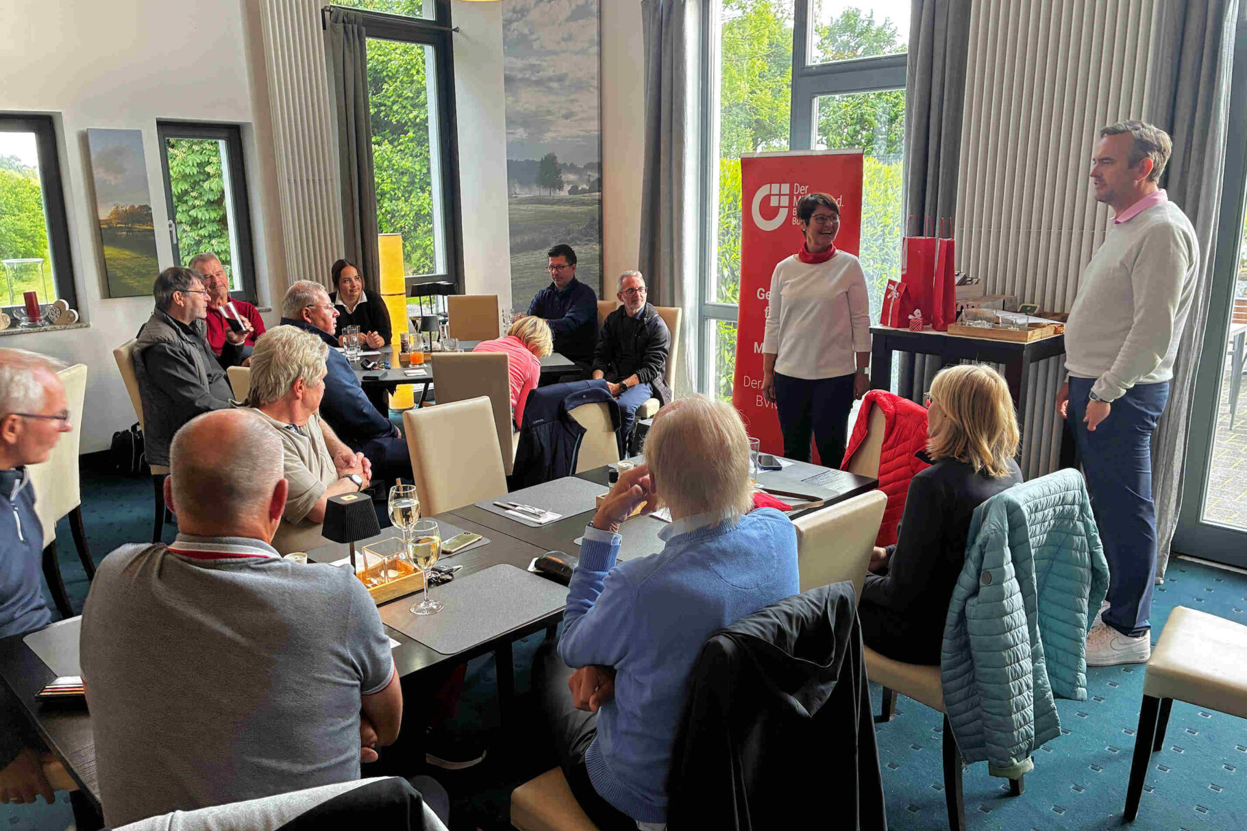 Barbara Herbst und der Manager Tiemo Müller vor den Golfteilnehmern