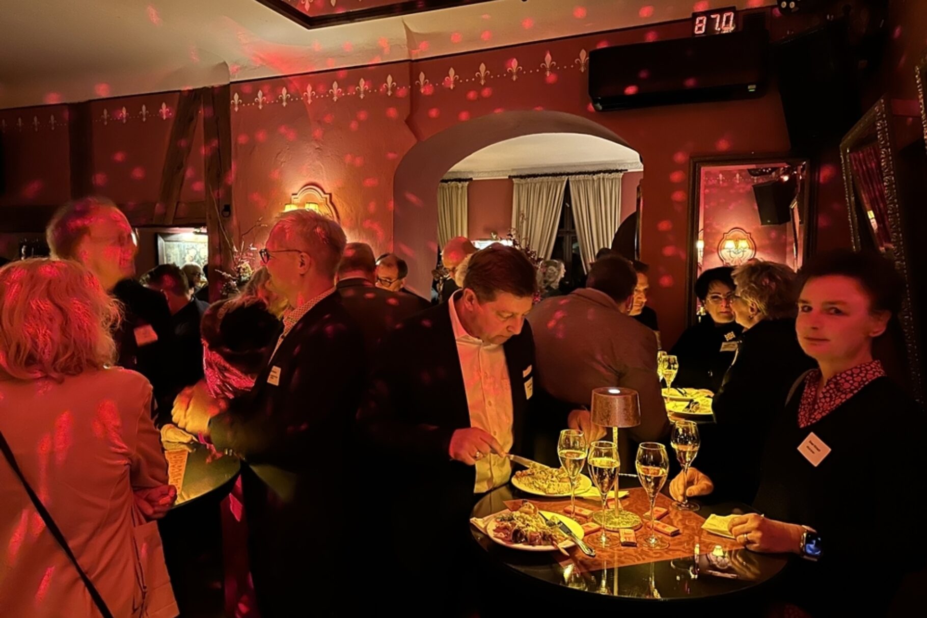 Menschen stehen um Stehtische - essen und unterhalten sich