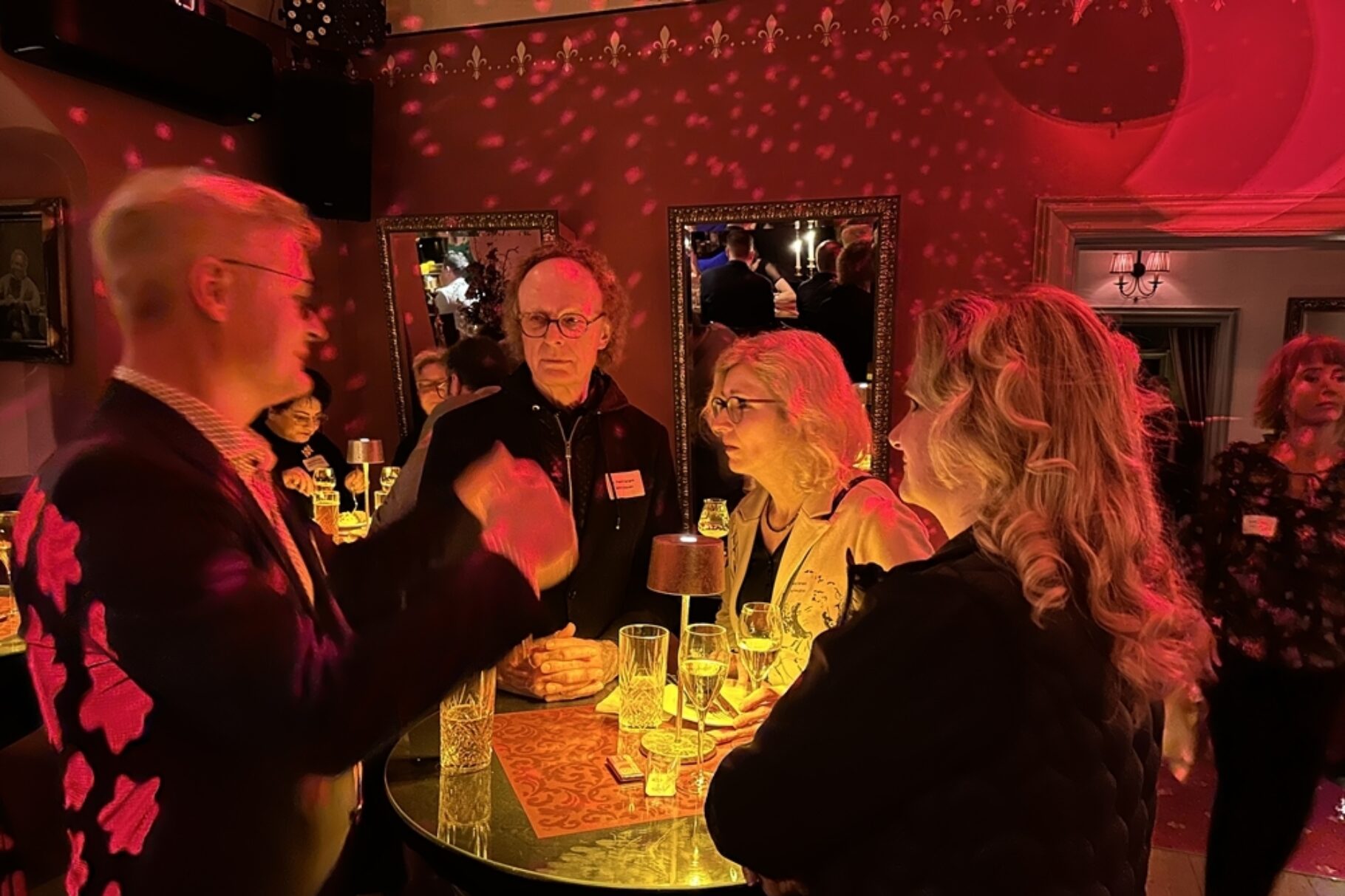 Vier Menschen Stehen um einen Tisch und unterhakten sich