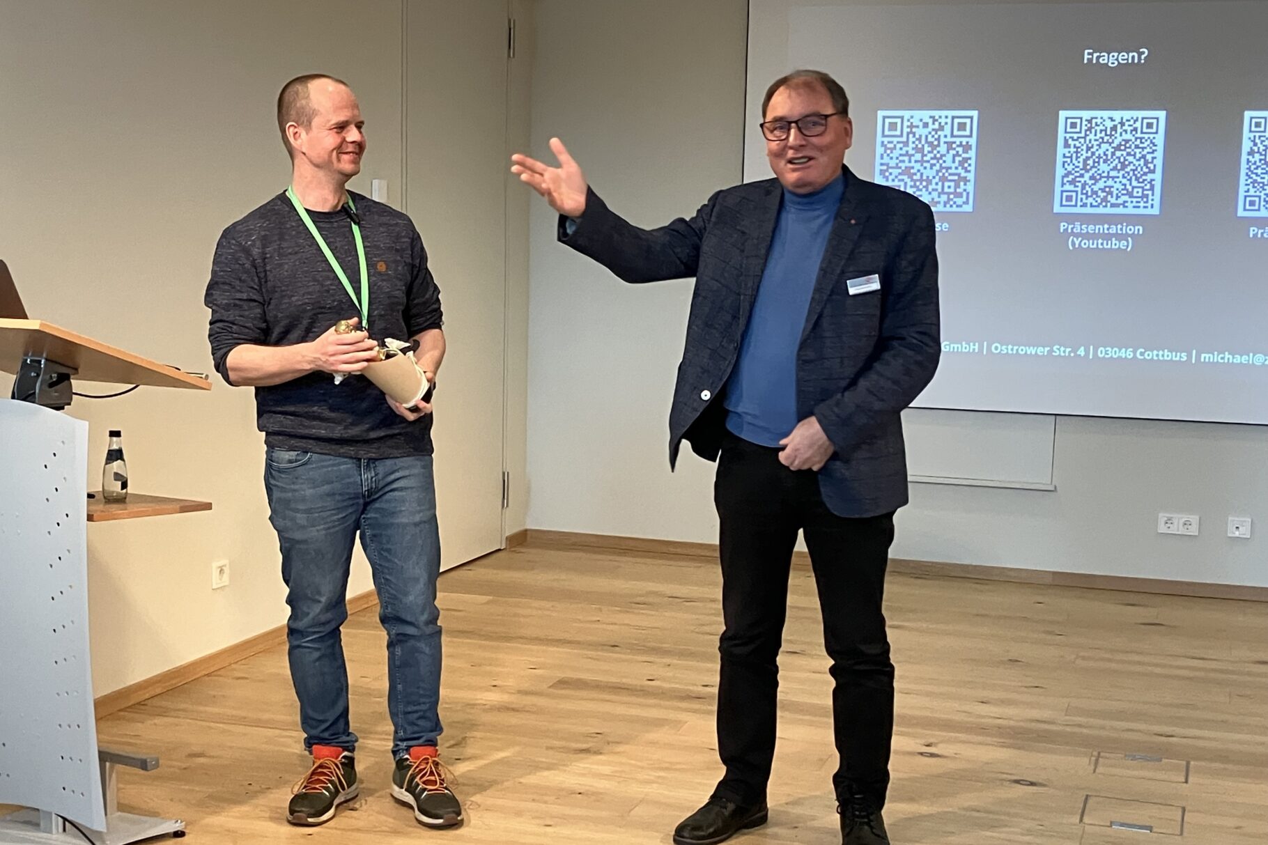 ein Mann überreicht an einen Referenten ein Präsent