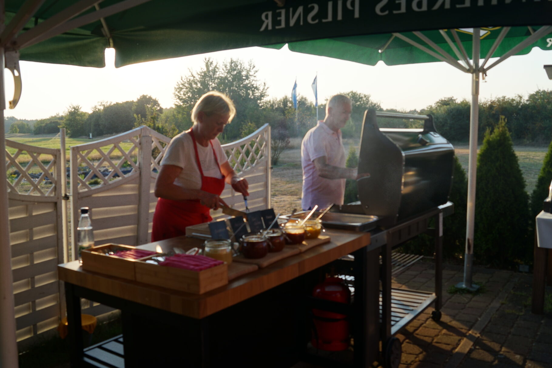 eine Frau und ein Mann stehen an einem Grill