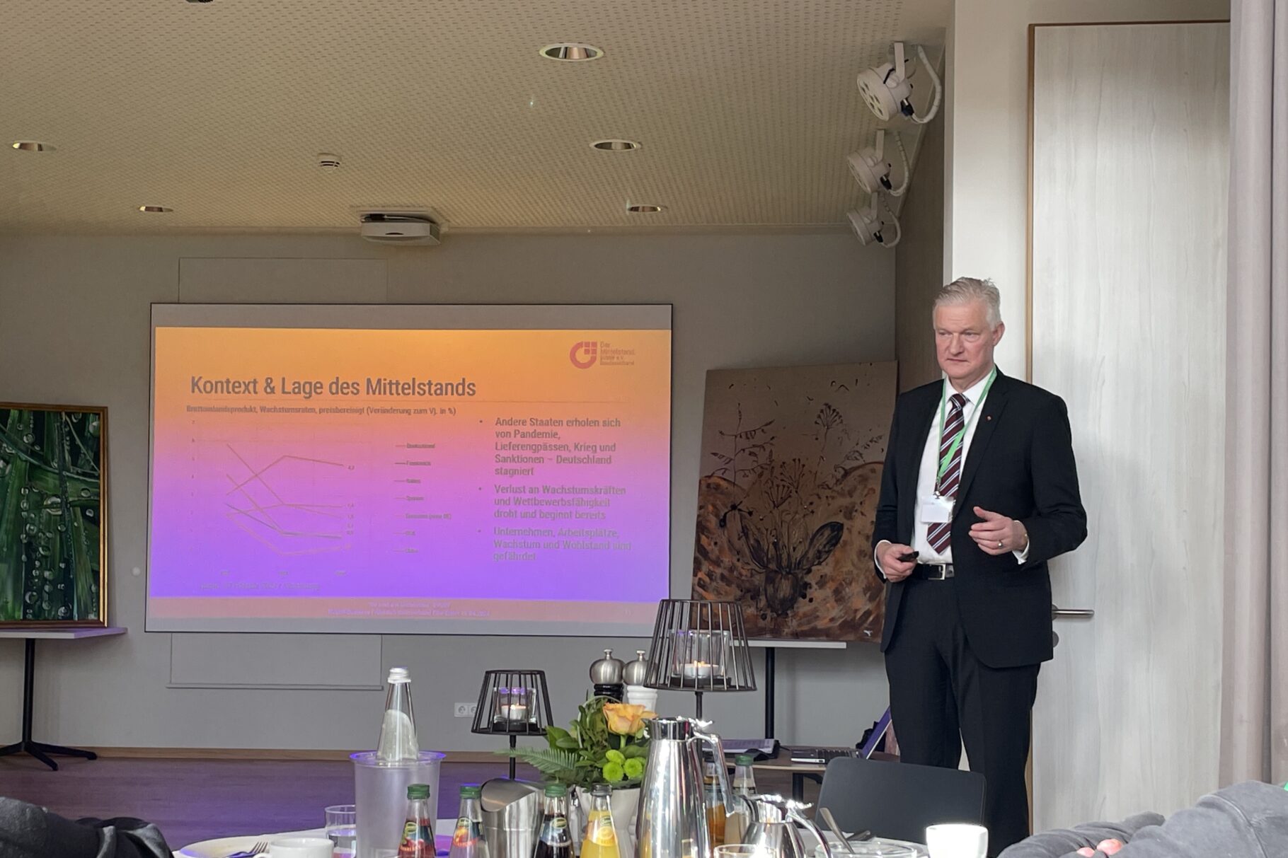 ein Mann steht vor einer Beamerleinwand und hält einen Vortrag