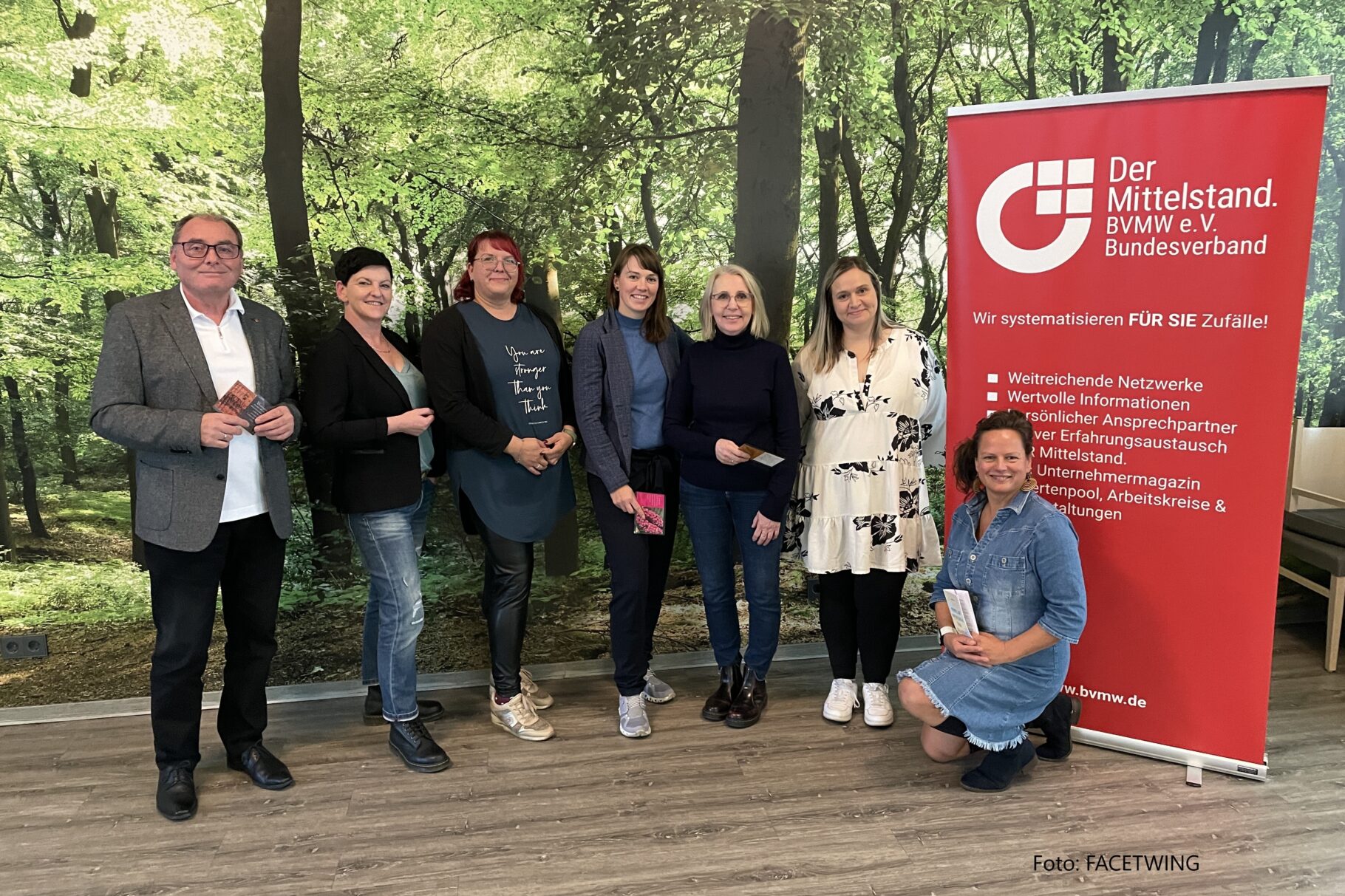 Teilnehmer*innen der Veranstaltung "Körper, Geist & Seele" stehen vor einem Plakat