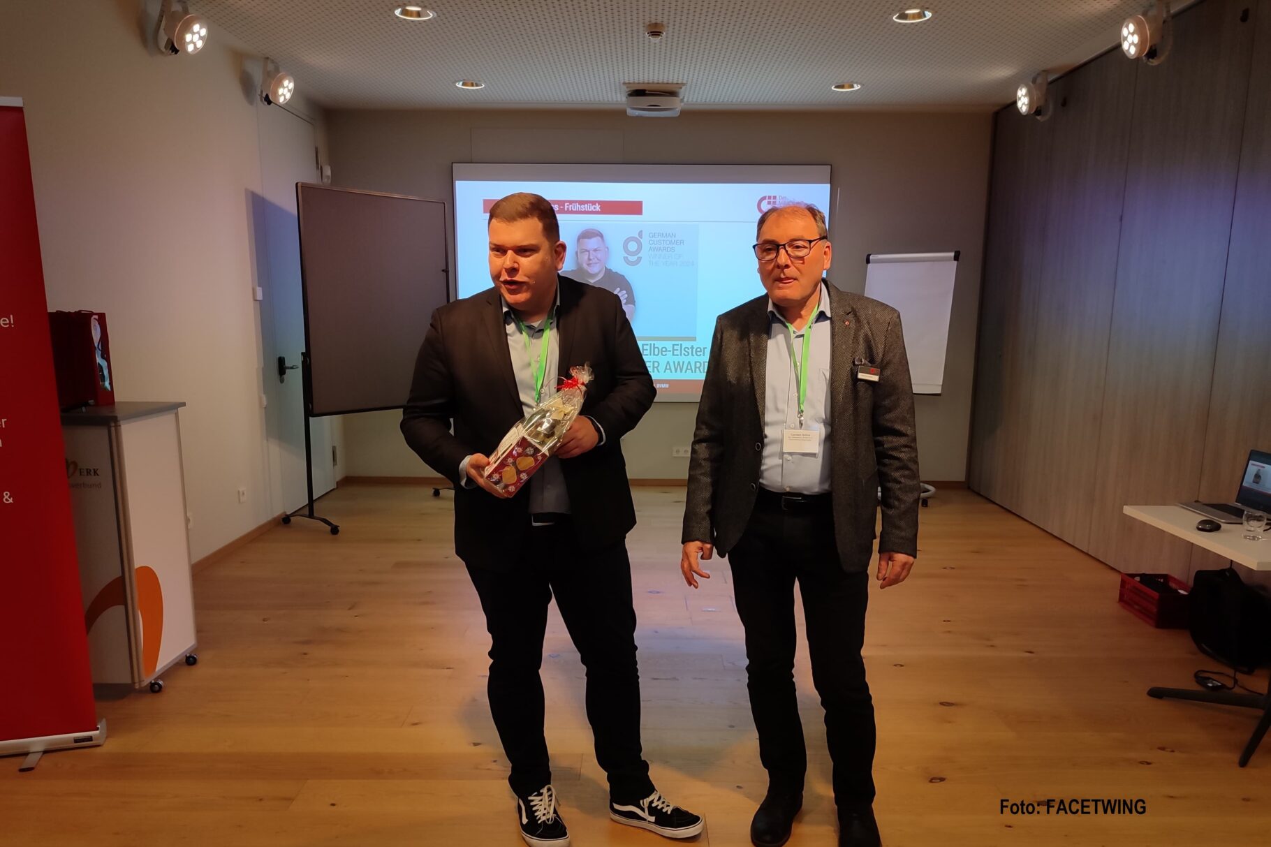 ein Mann gratuliert einem anderen Mann und überreicht ein Präsent