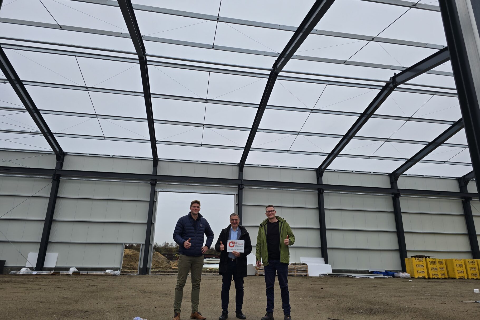 Drei Männer stehen in der Mitte einer Halle