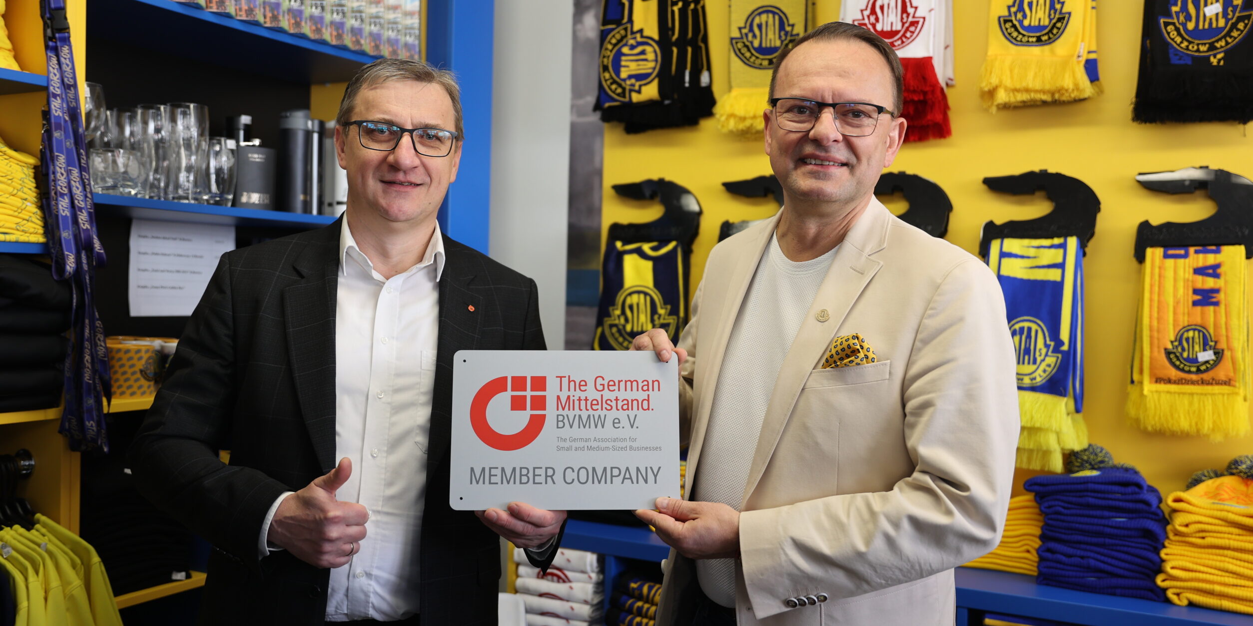 zwei Männer halten ein Mitgliedsschild in die Höhe