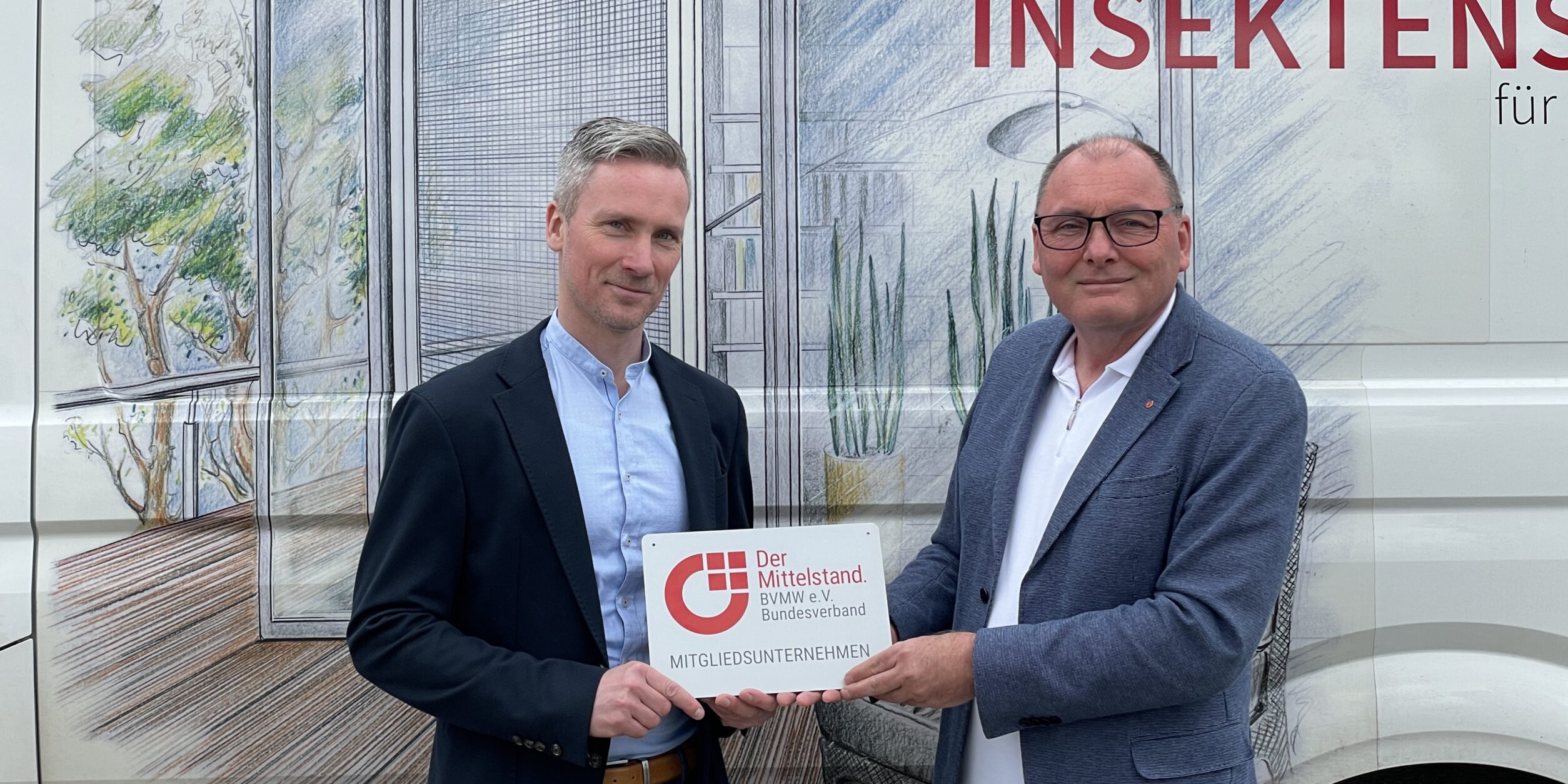 zwei Männer stehen vor einem Transporter und halten ein Schild in der Hand