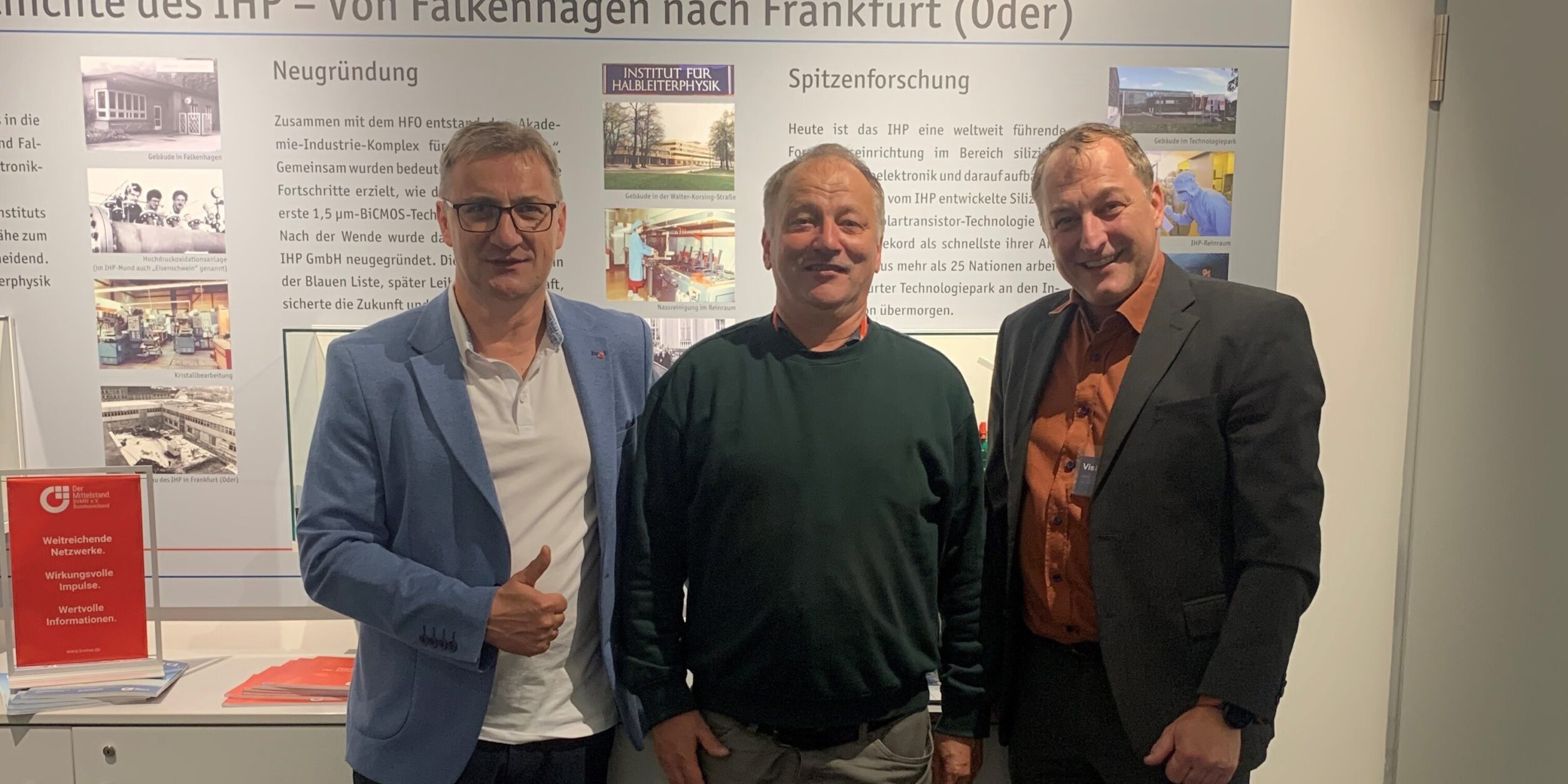 drei Männer stehen vor einer Infotafel