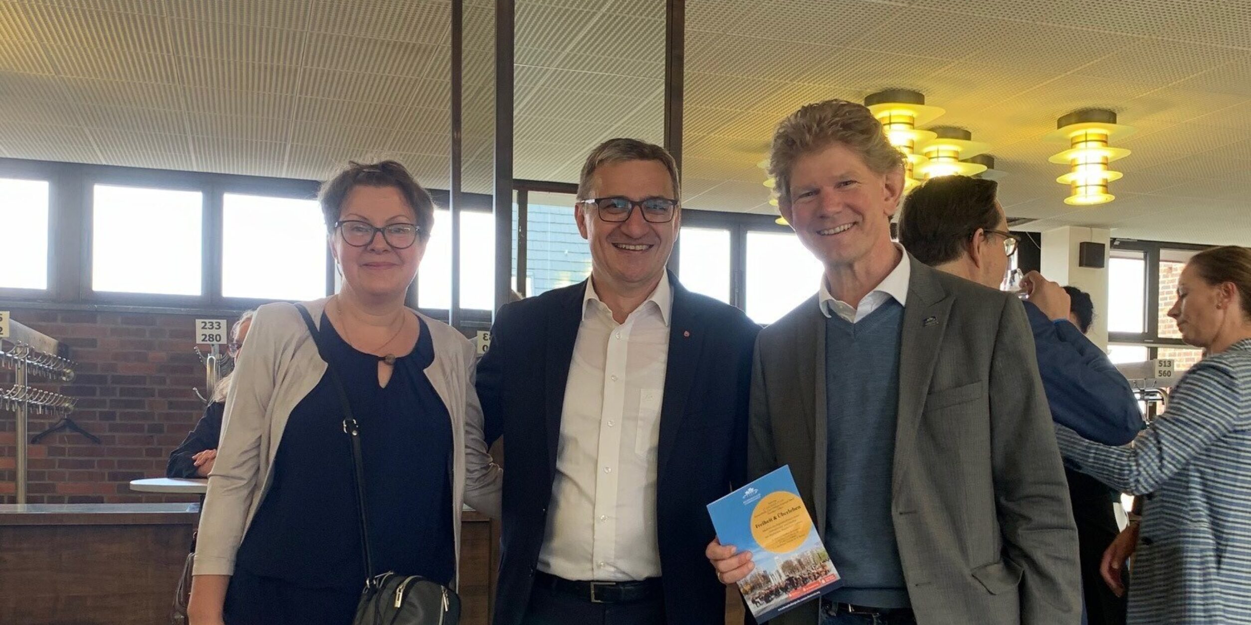 eine Frau und zwei Männer stehen in einer Halle